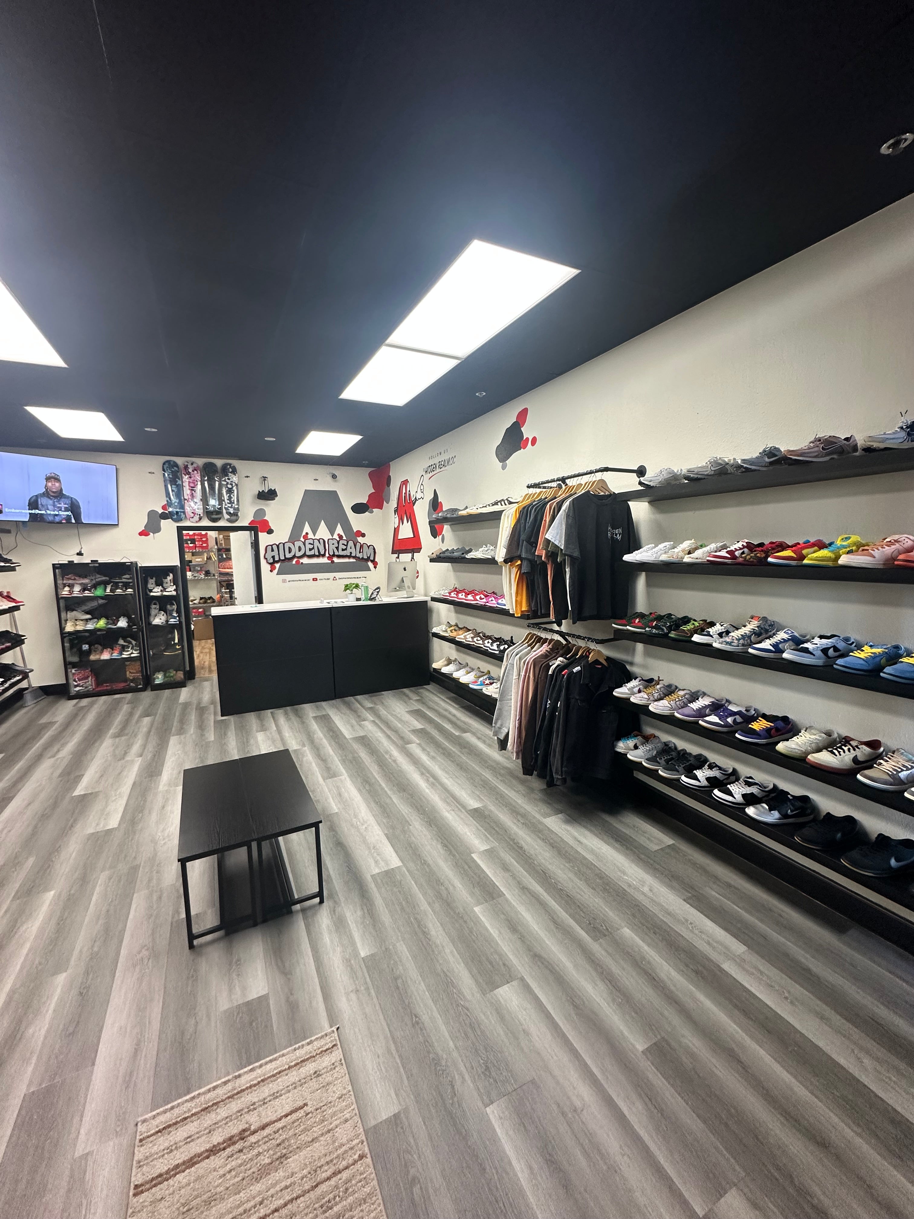 Interior view of Hidden Realm Sneaker Shop showcasing shelves with Jordans, SB Dunks, Yeezys, and streetwear apparel for sneaker resale.