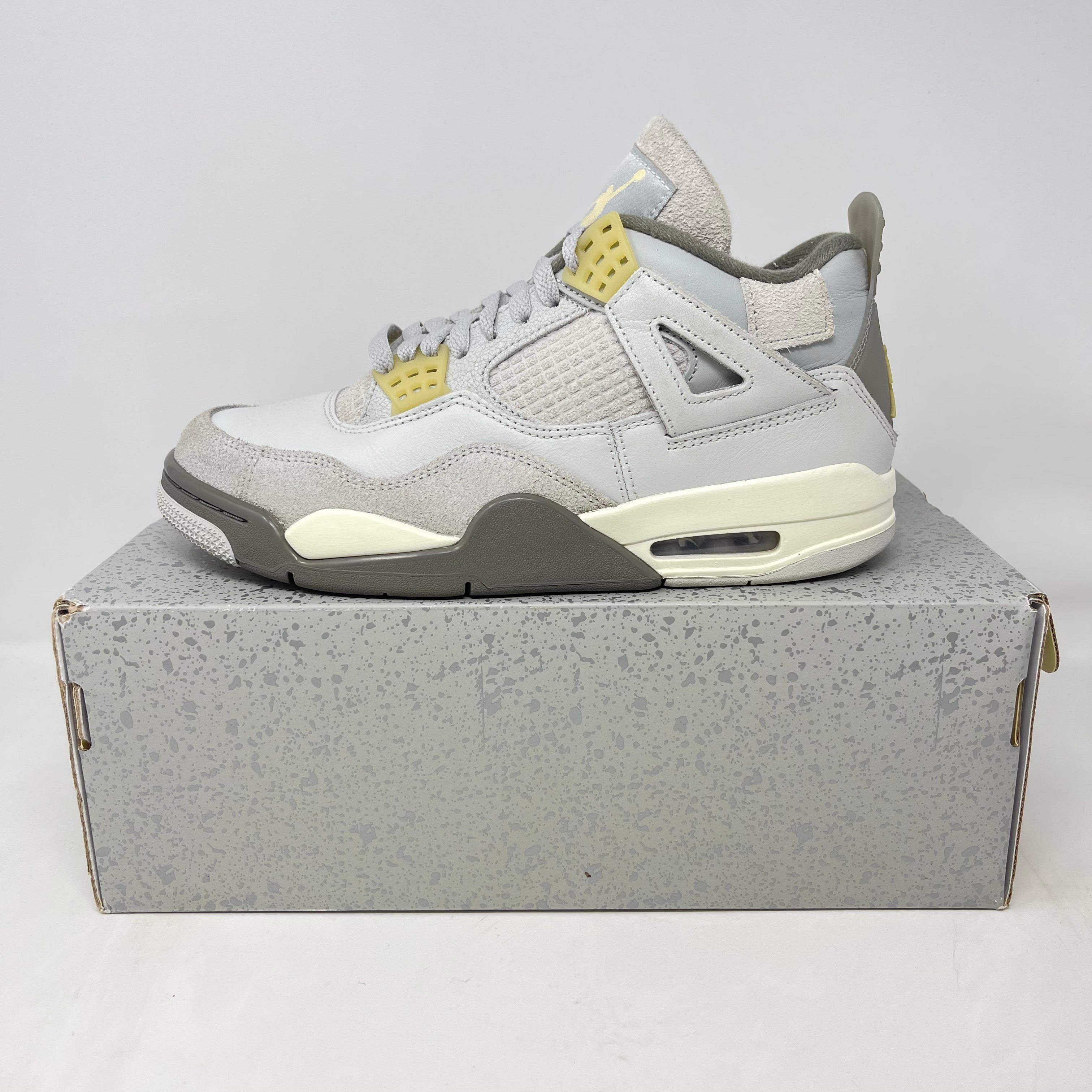 Light grey and yellow Air Jordan 4 sneaker on a speckled grey shoebox, showcasing a popular sneaker drop in Southern California.