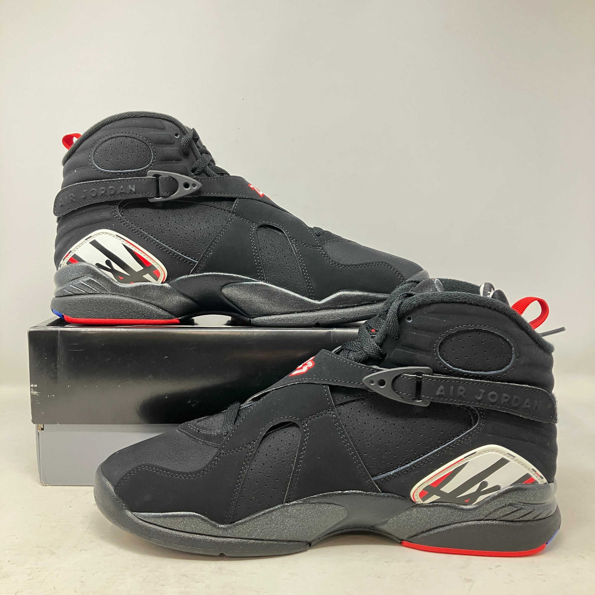 Air Jordan sneakers in black leather and suede with midfoot straps, red accents, and white graphic heel panels for Sneaker Drops Orange County.
