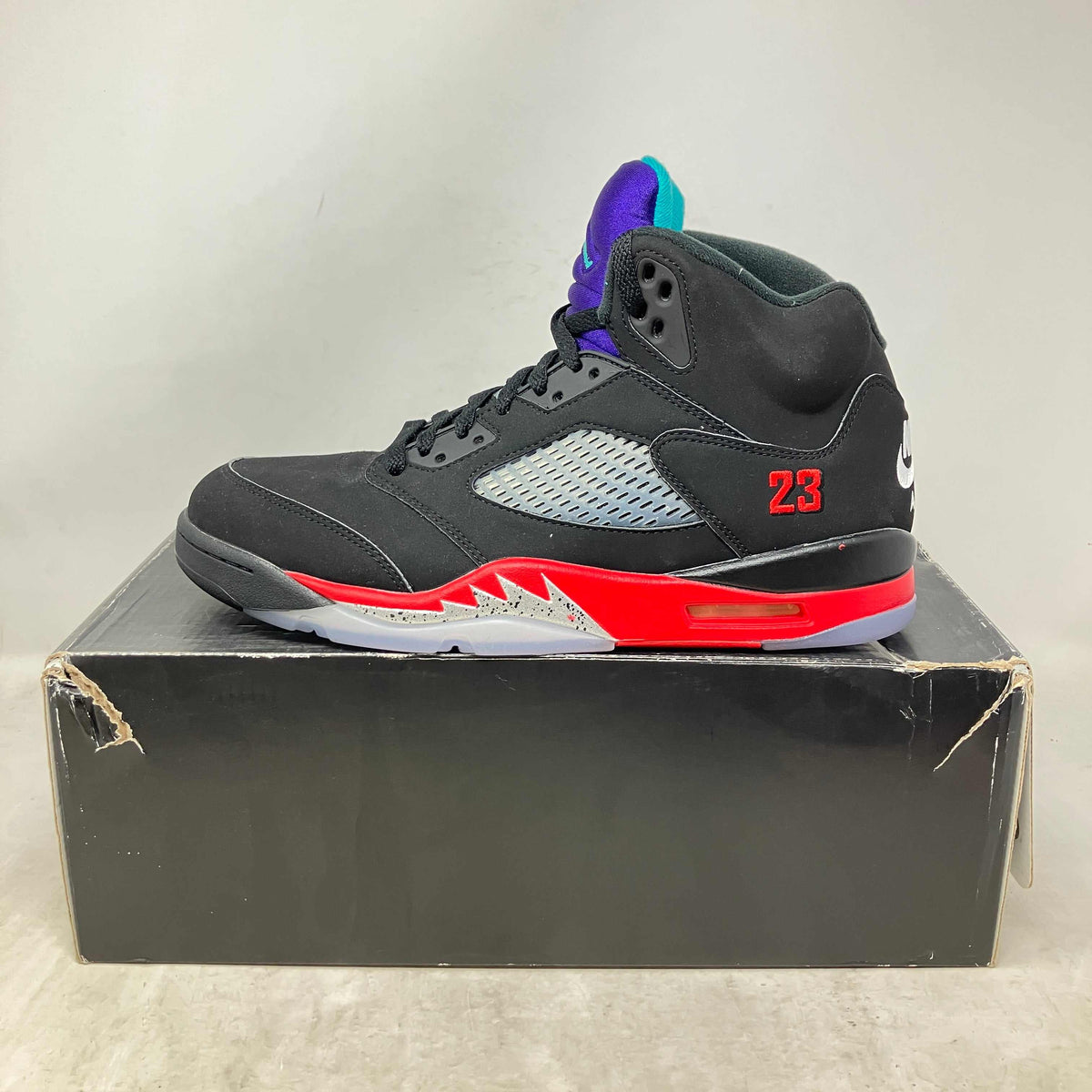 Jordan 5 Retro black sneaker with red and purple accents, mesh side panel, and embroidered number 23 on the heel.