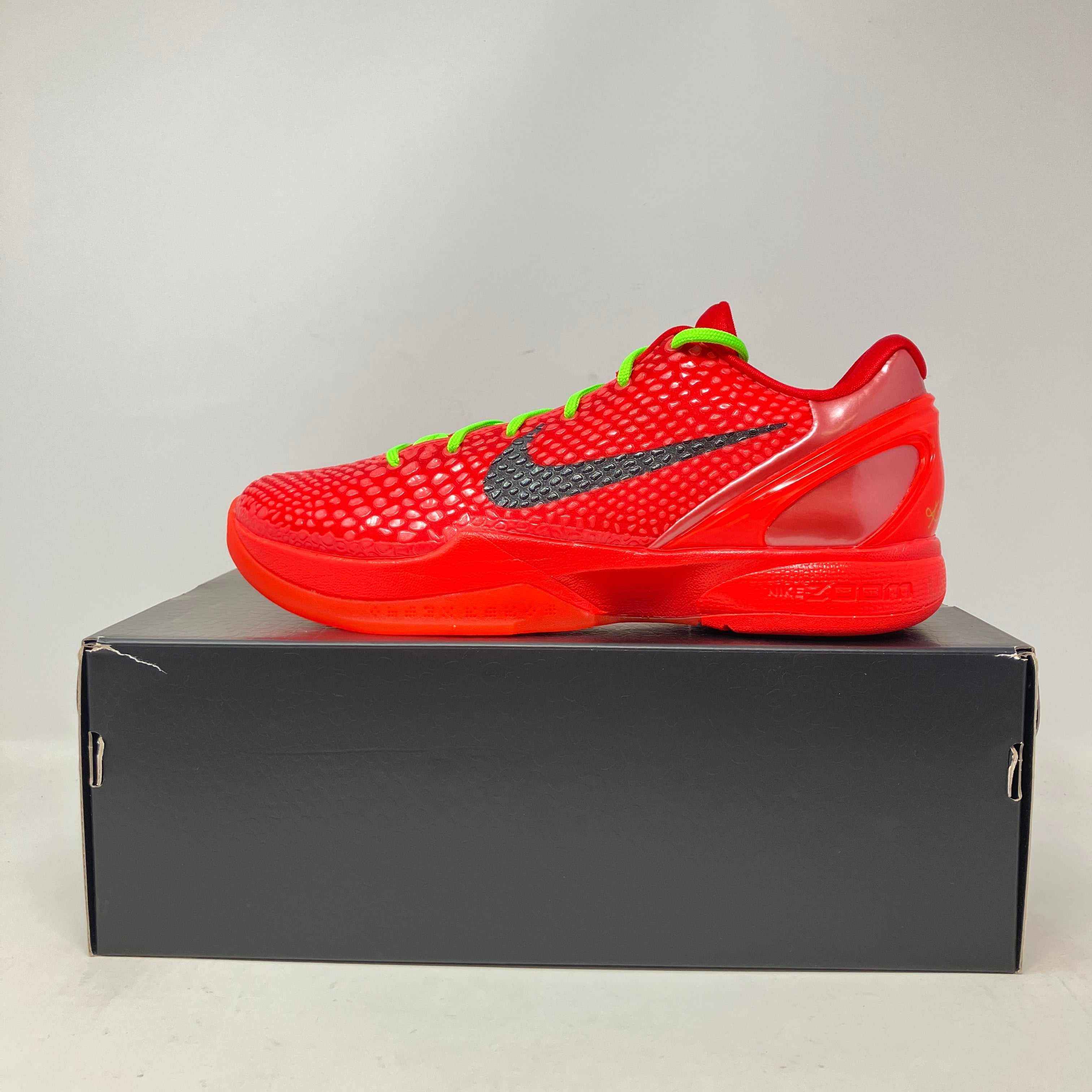 Nike Kobe 6 Protro Reverse Grinch red basketball shoe on black box, pre-owned with accessories included