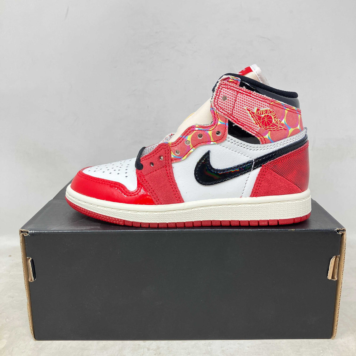 Jordan 1 Retro High OG high-top sneaker in red, white, and black with Spider-Man themed graphic details and suede accents.