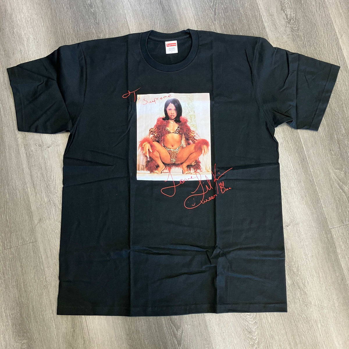 Black cotton Supreme Lil Kim Tee featuring a large graphic photo of Lil Kim in a fur coat and leopard print outfit with red signature text.