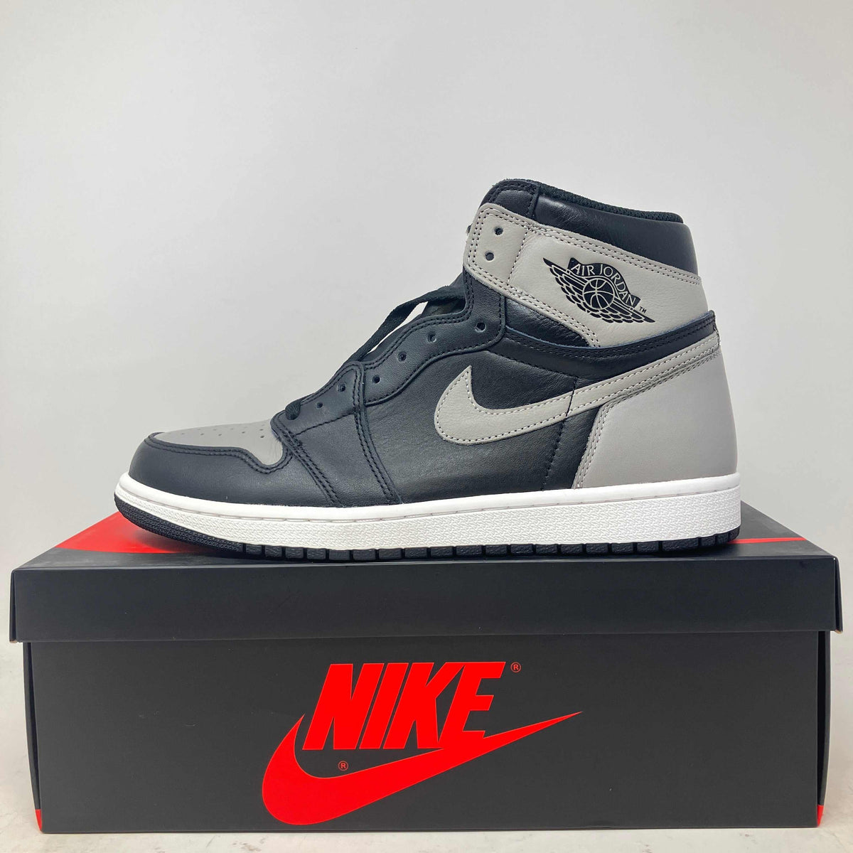 Jordan 1 Retro High Shadow high-top sneaker in black and grey leather, with a white Swoosh and textured white sole.