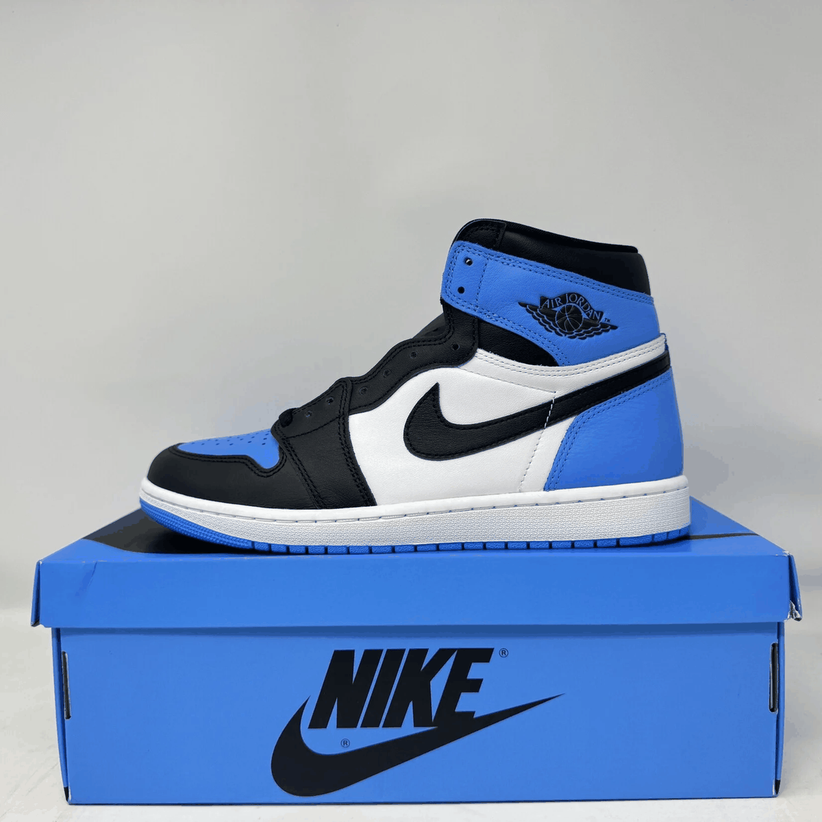 Jordan 1 Retro high-top sneaker in black, blue, and white leather with Nike swoosh and Air Jordan wings logo.