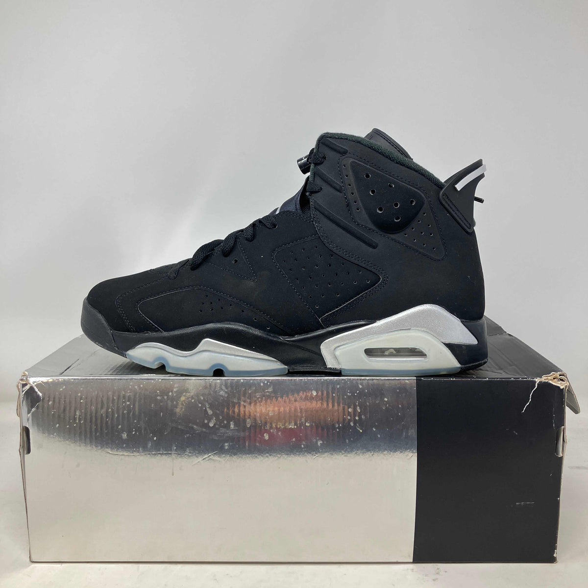 Black and silver suede basketball shoe with perforated detailing and reflective accents on a silver box, Jordan 6 Retro Chrome