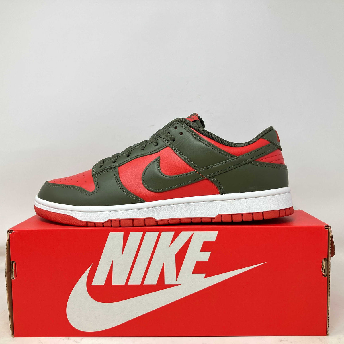 Nike Dunk Low sneaker in bright red and dark olive leather, with a matching Swoosh and red rubber outsole.