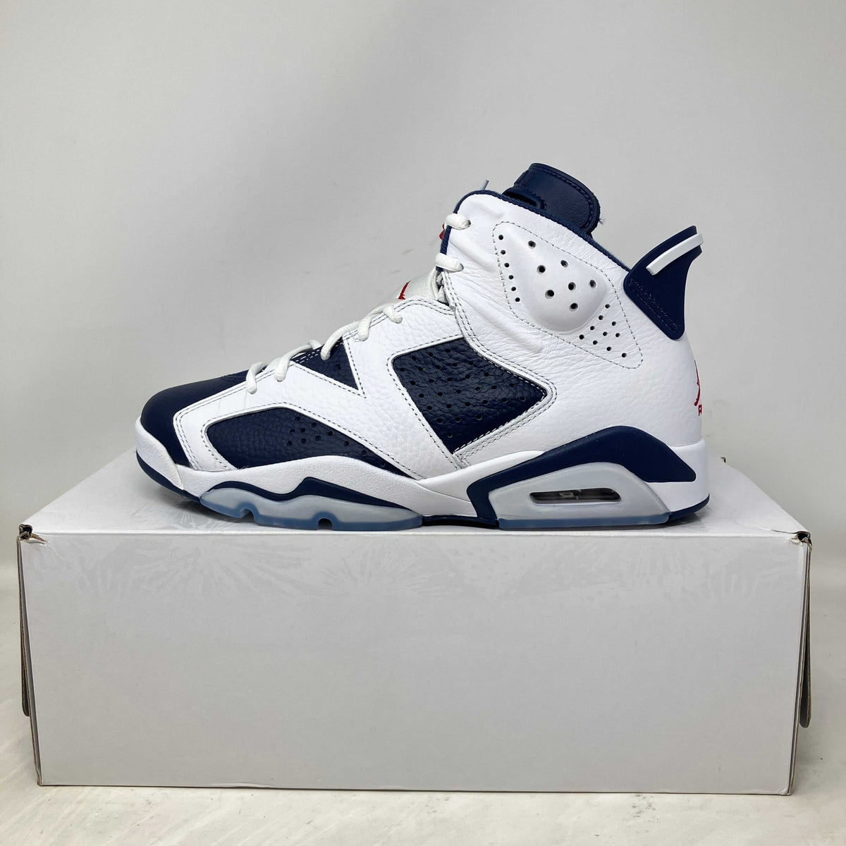 Jordan 6 Retro basketball shoe in white and navy blue leather with perforated detailing and visible air sole unit.