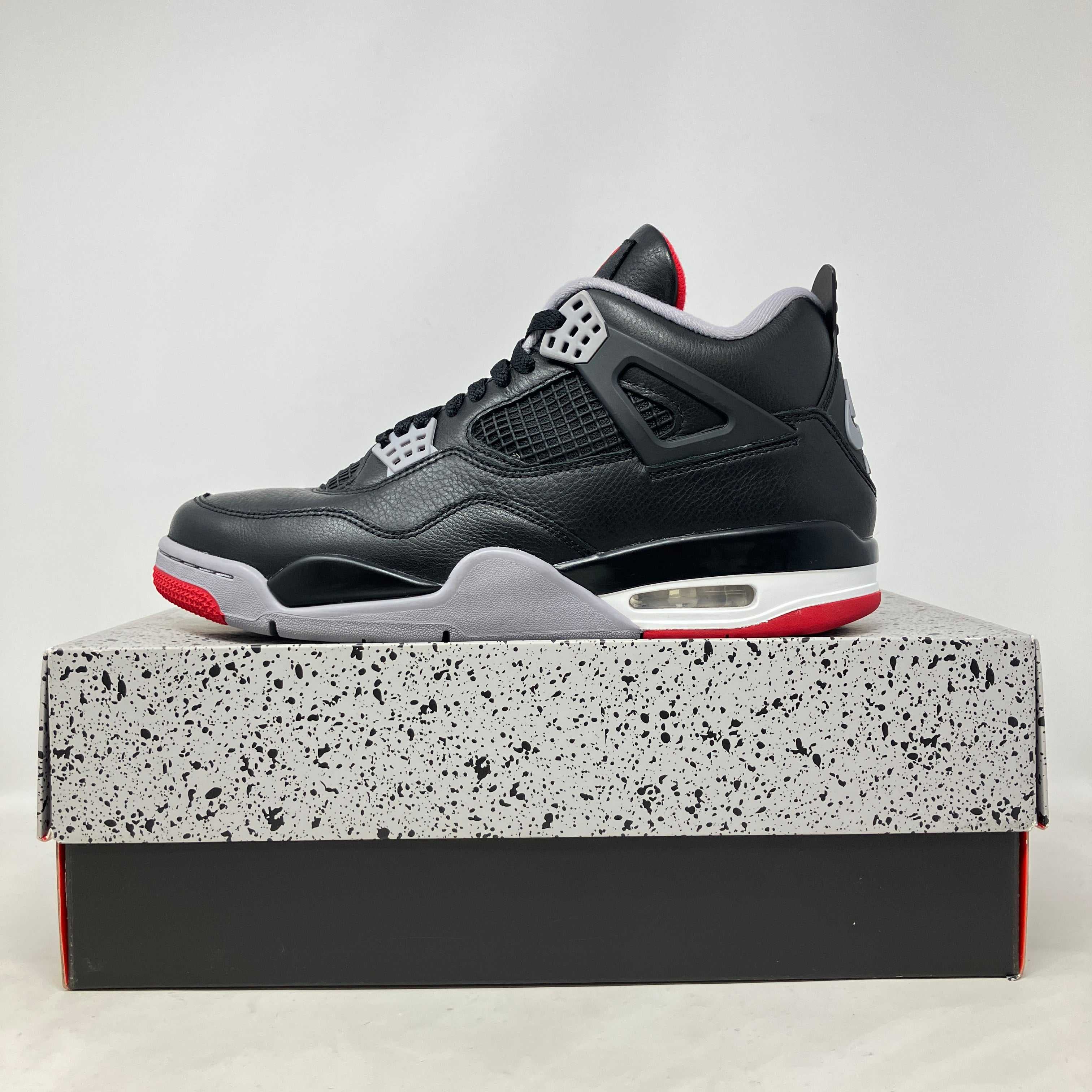 Jordan 4 Retro Bred Reimagined black and red sneaker on speckled box pre-owned with accessories