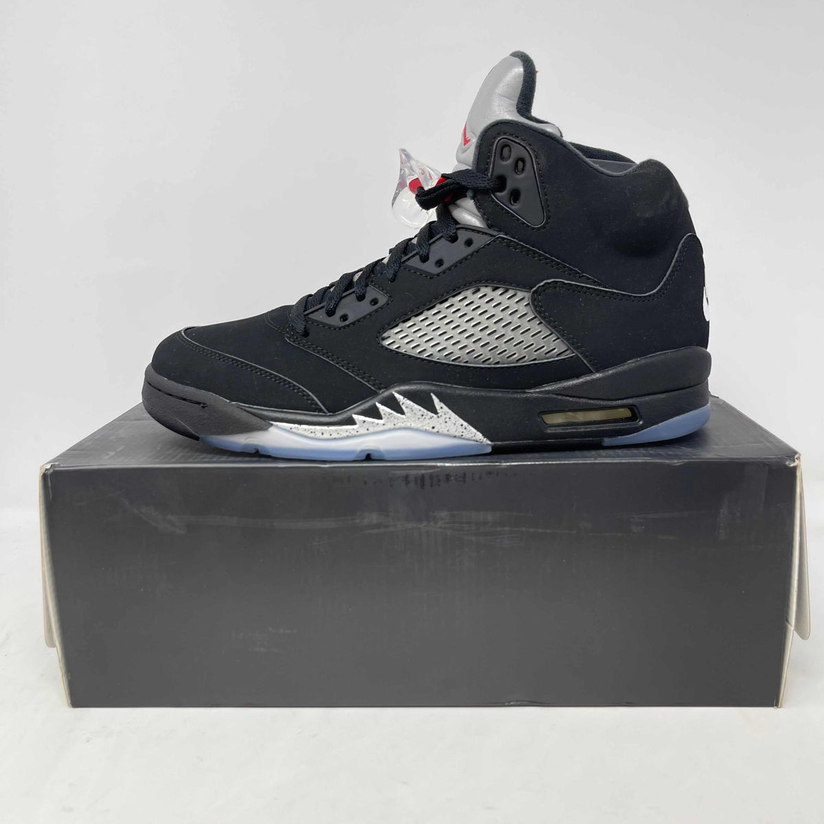Jordan 5 Retro black and metallic silver sneaker with mesh side panel and translucent sole on a black shoebox.