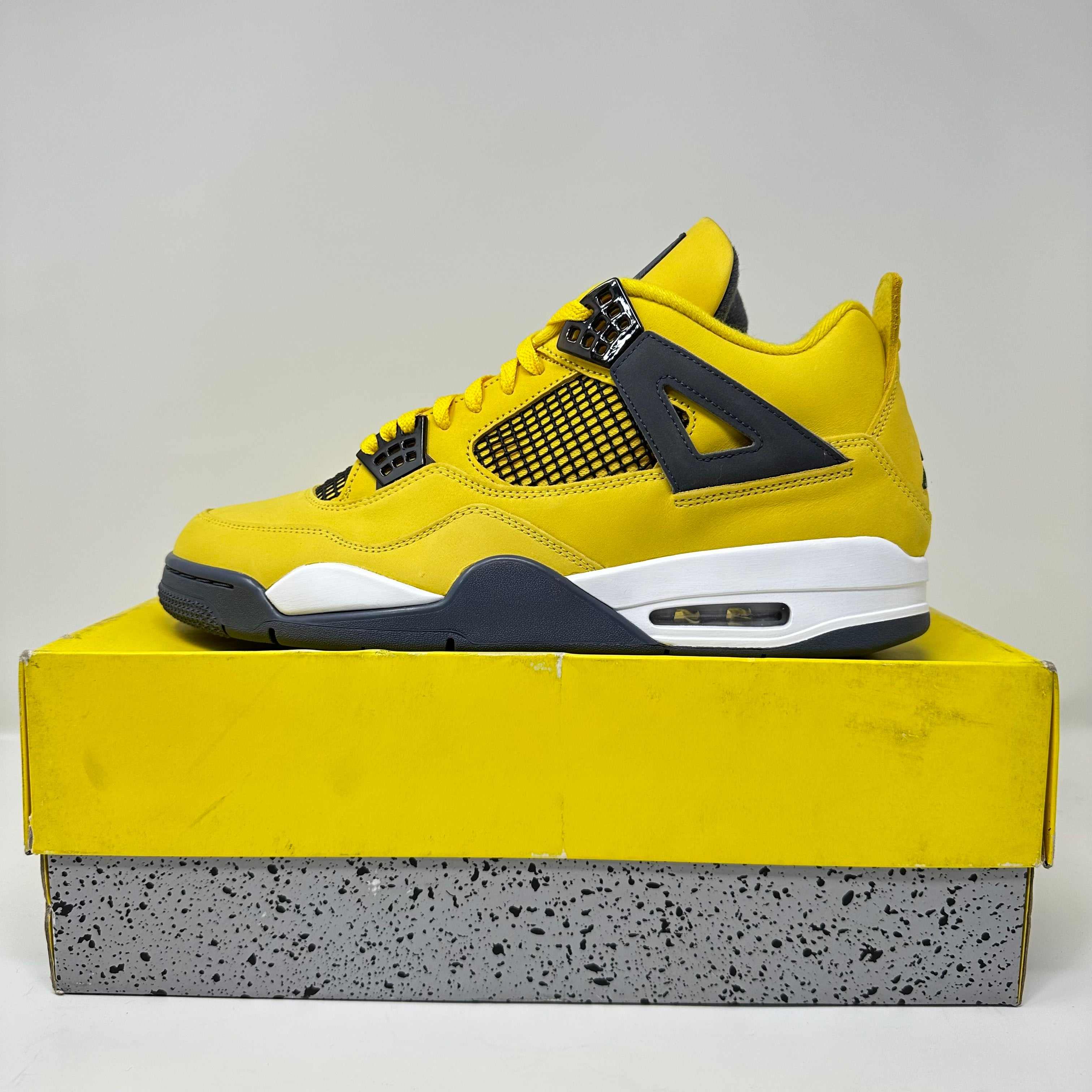 Jordan 4 Retro Lightning 2021 yellow and black sneaker on yellow and speckled box, brand new with accessories included