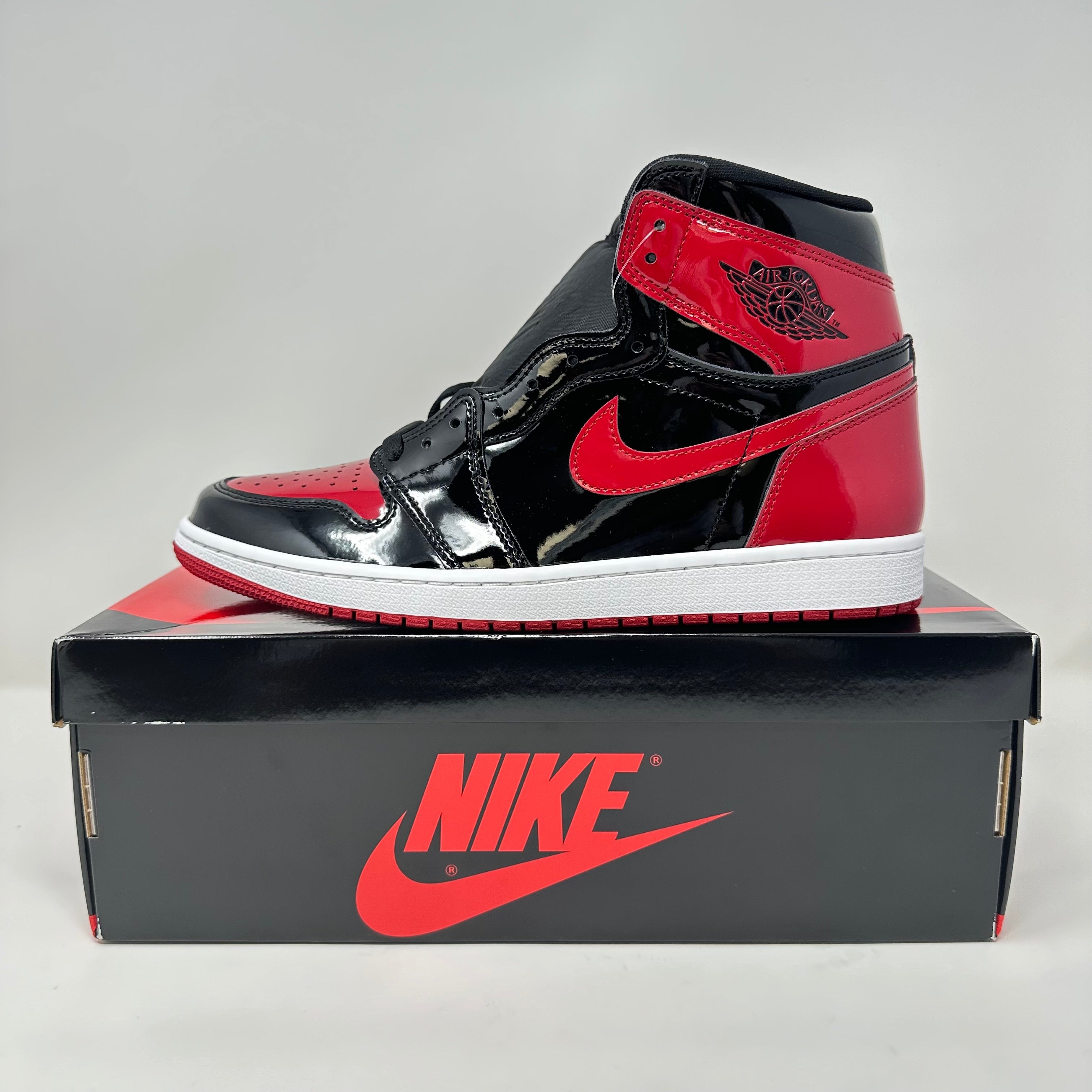 Jordan 1 Retro High OG Patent Bred sneaker in black and red patent leather on Nike box, brand new with all accessories included