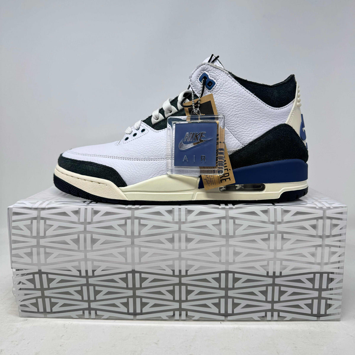 Jordan 3 Retro white leather sneaker with black, diffused blue accents, and textured black detailing on a patterned box.