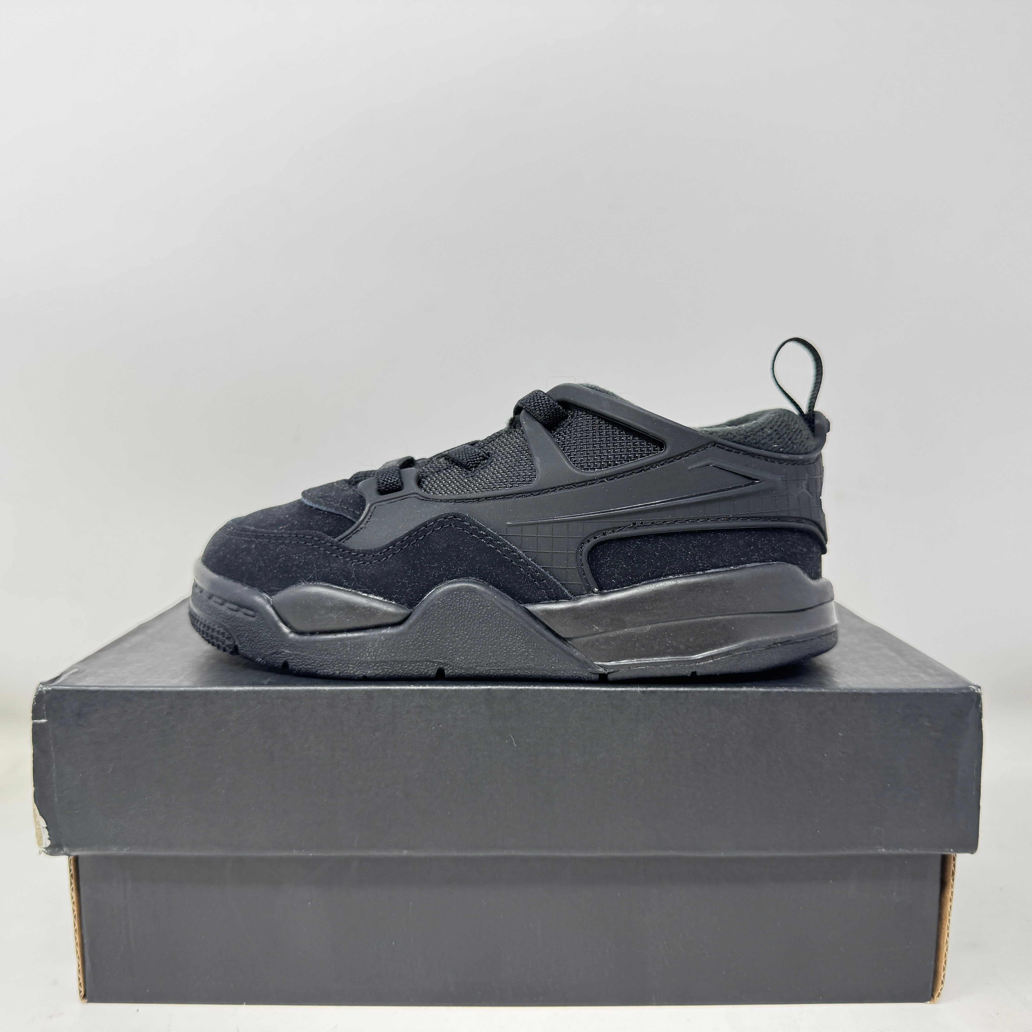 Side view of brand new Jordan 4 RM Black Cat toddler sneaker on black box