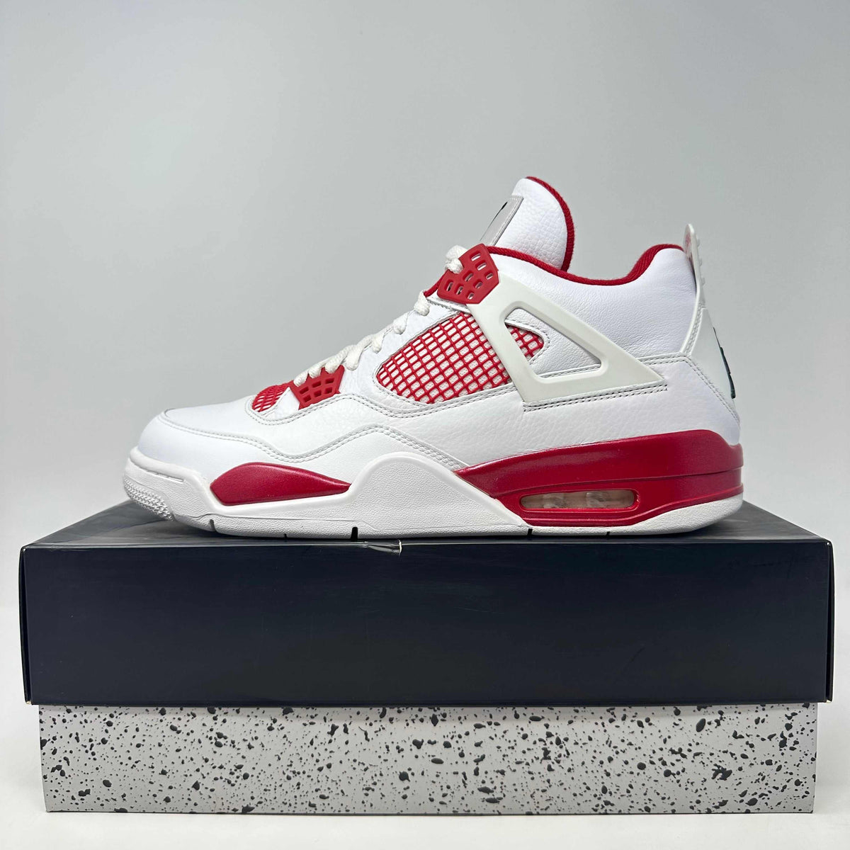 Jordan 4 Retro white and red leather sneaker with mesh side panels and visible air cushioning in the sole.