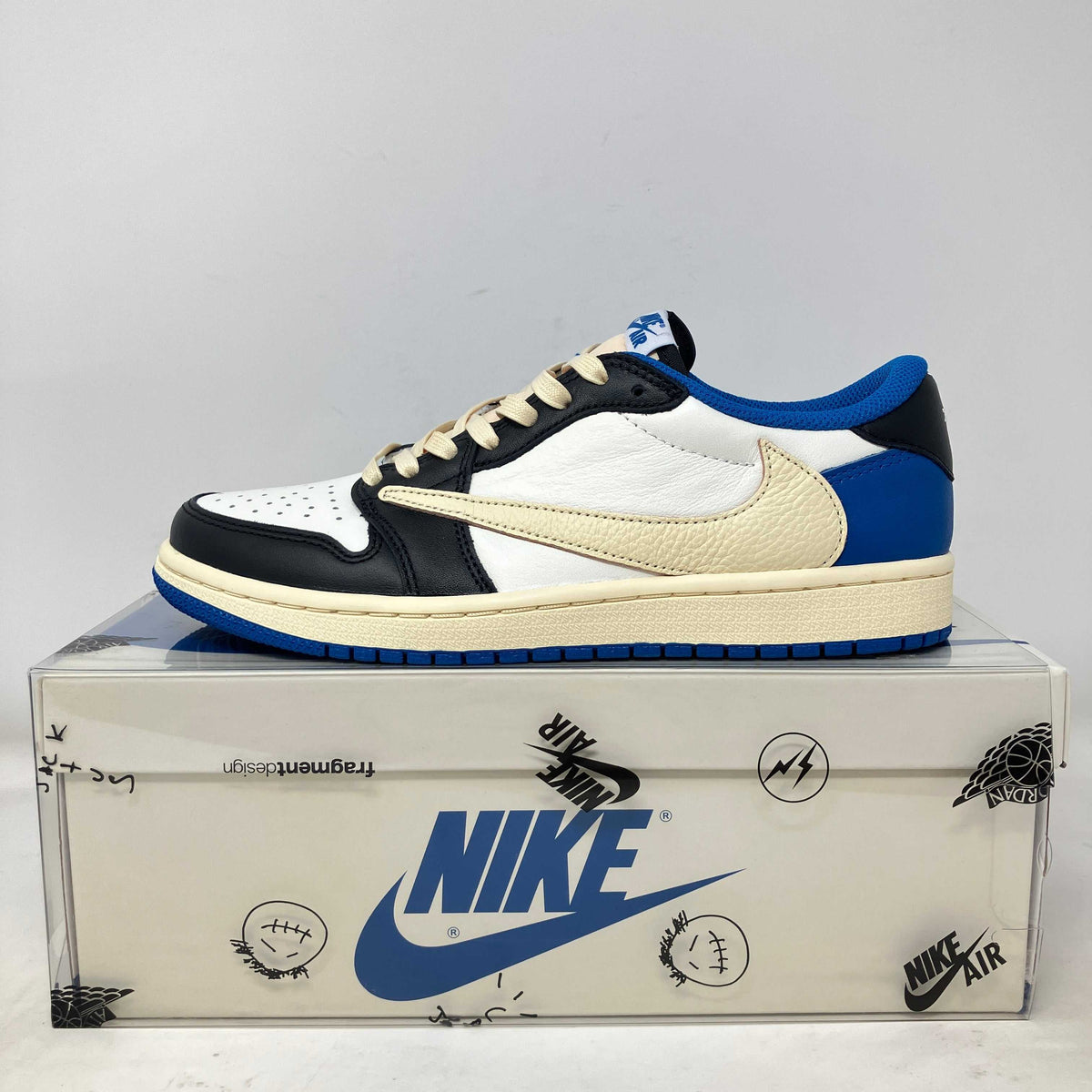 Jordan 1 Retro Low OG sneaker in white leather with black overlays, blue accents, and a cream reversed Swoosh.