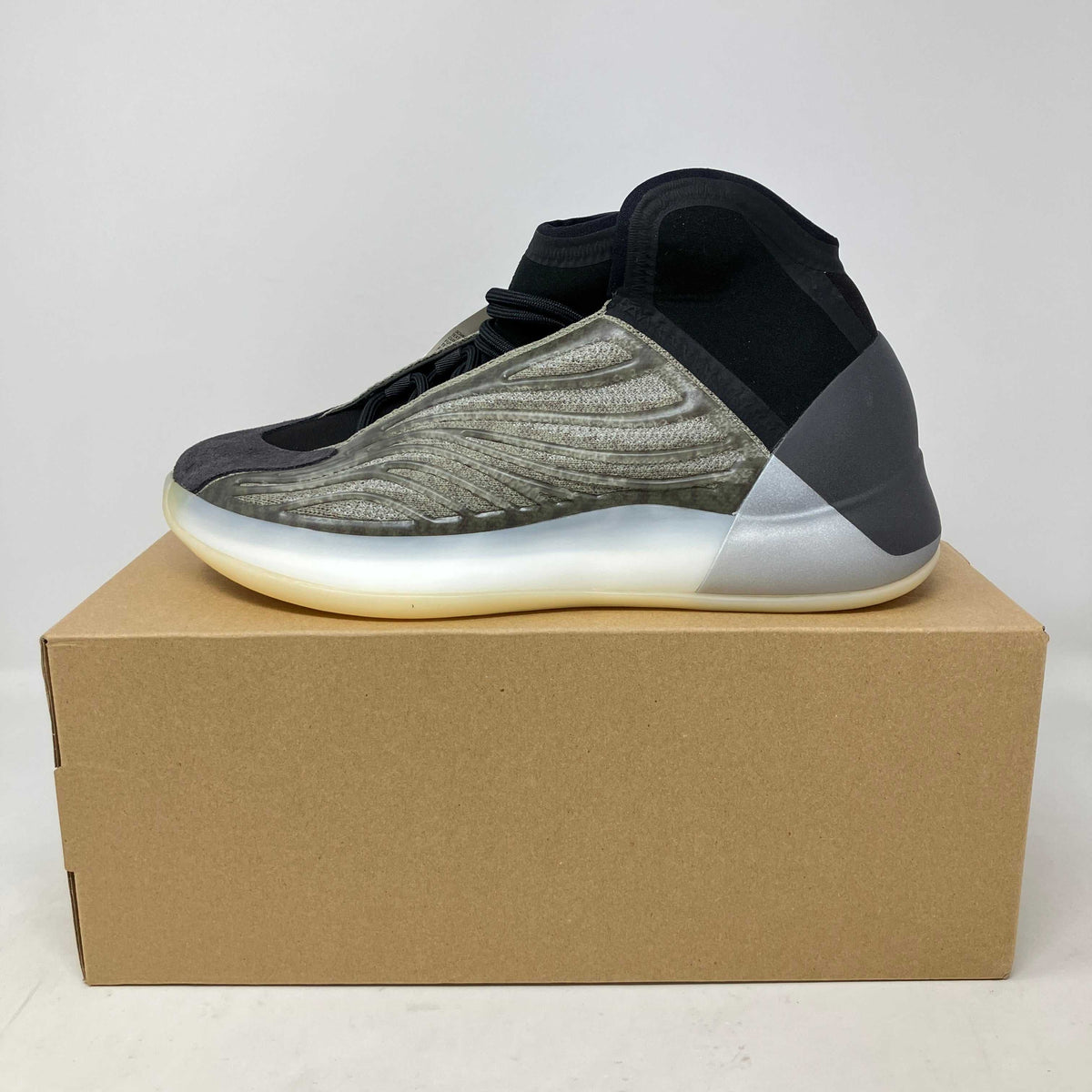 adidas Yeezy QNTM high-top sneakers in grey and black with textured side panels and translucent sole on a cardboard box