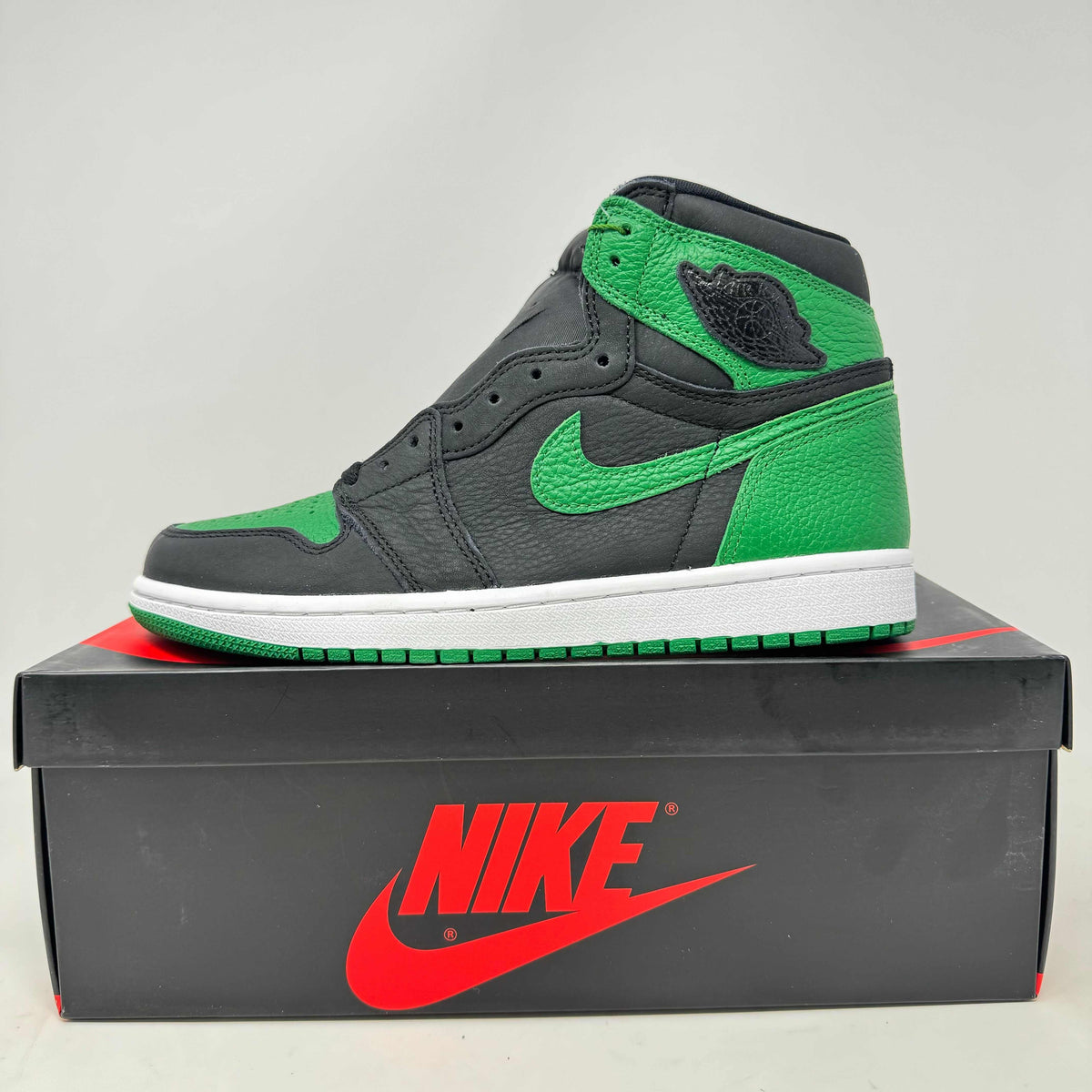Jordan 1 Retro High sneaker in black and pine green leather with white midsole and Nike branding on box.