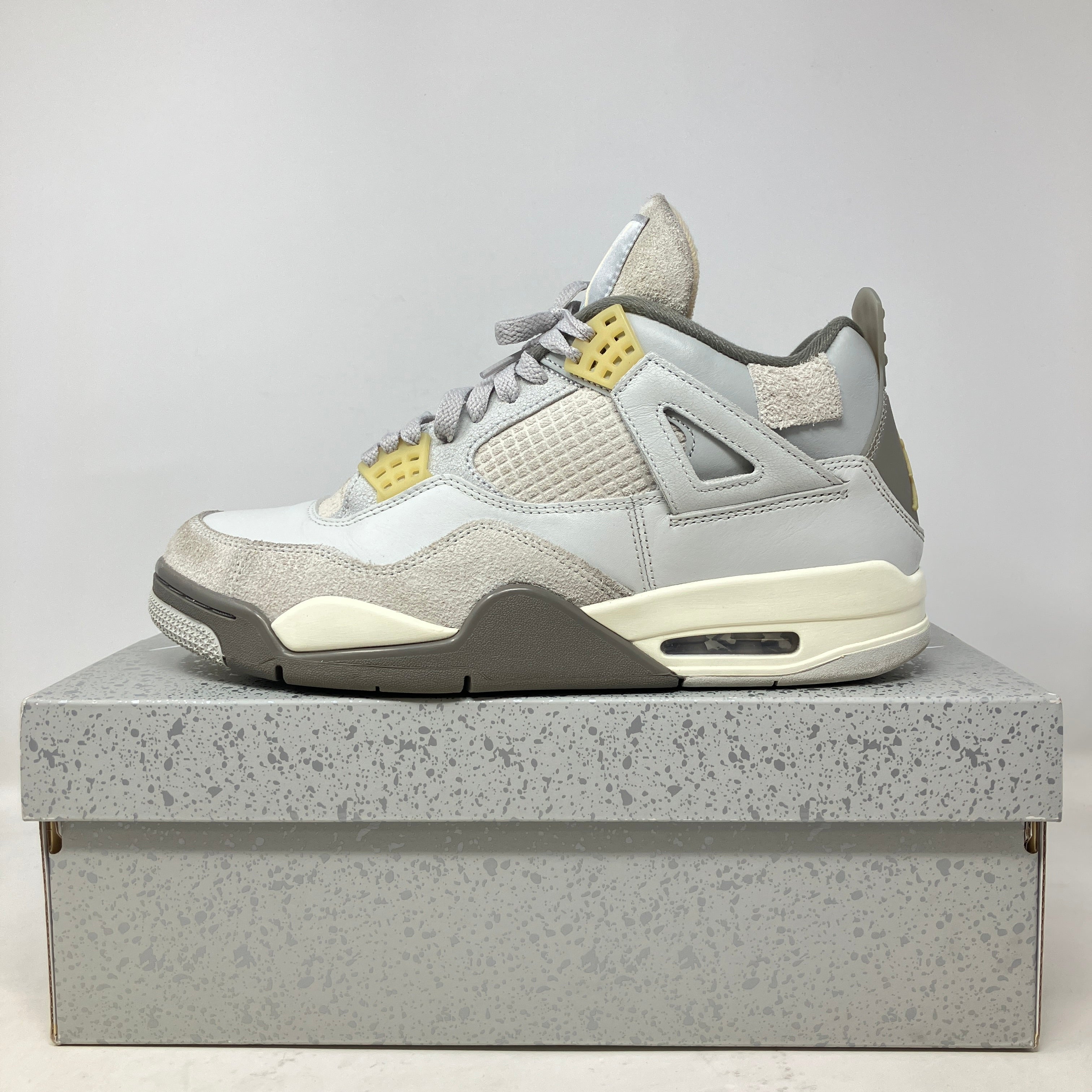 Side view of pre-owned Jordan 4 Retro SE Craft Photon Dust sneaker on speckled gray box with all accessories included