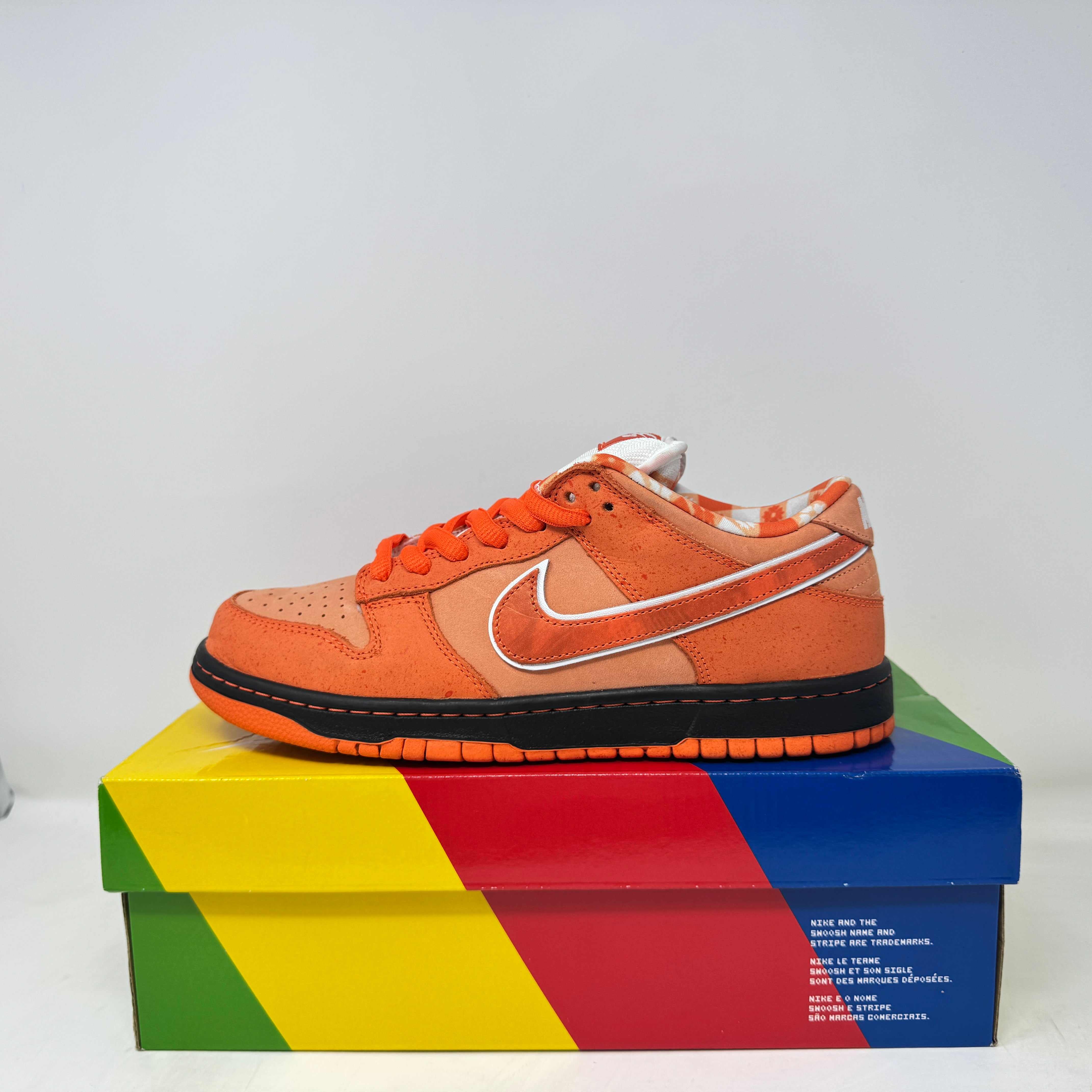 Nike SB Dunk Low Concepts Orange Lobster sneaker on colorful box, pre-owned condition