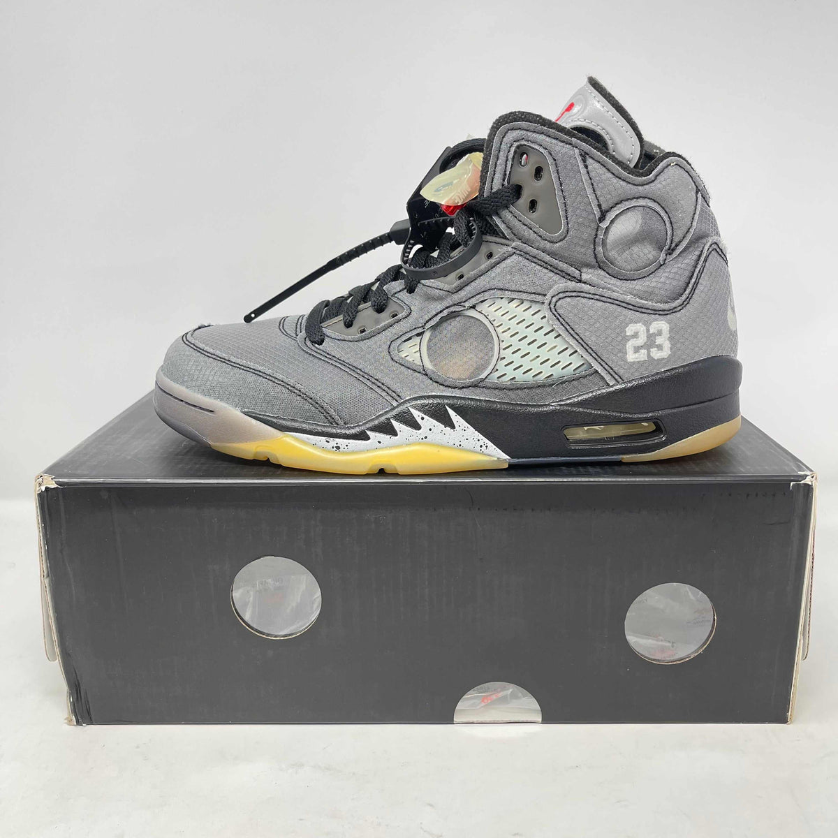 Jordan 5 Retro high-top sneaker in gray suede and mesh, with black laces, translucent panels, yellow accents and 23 detail.
