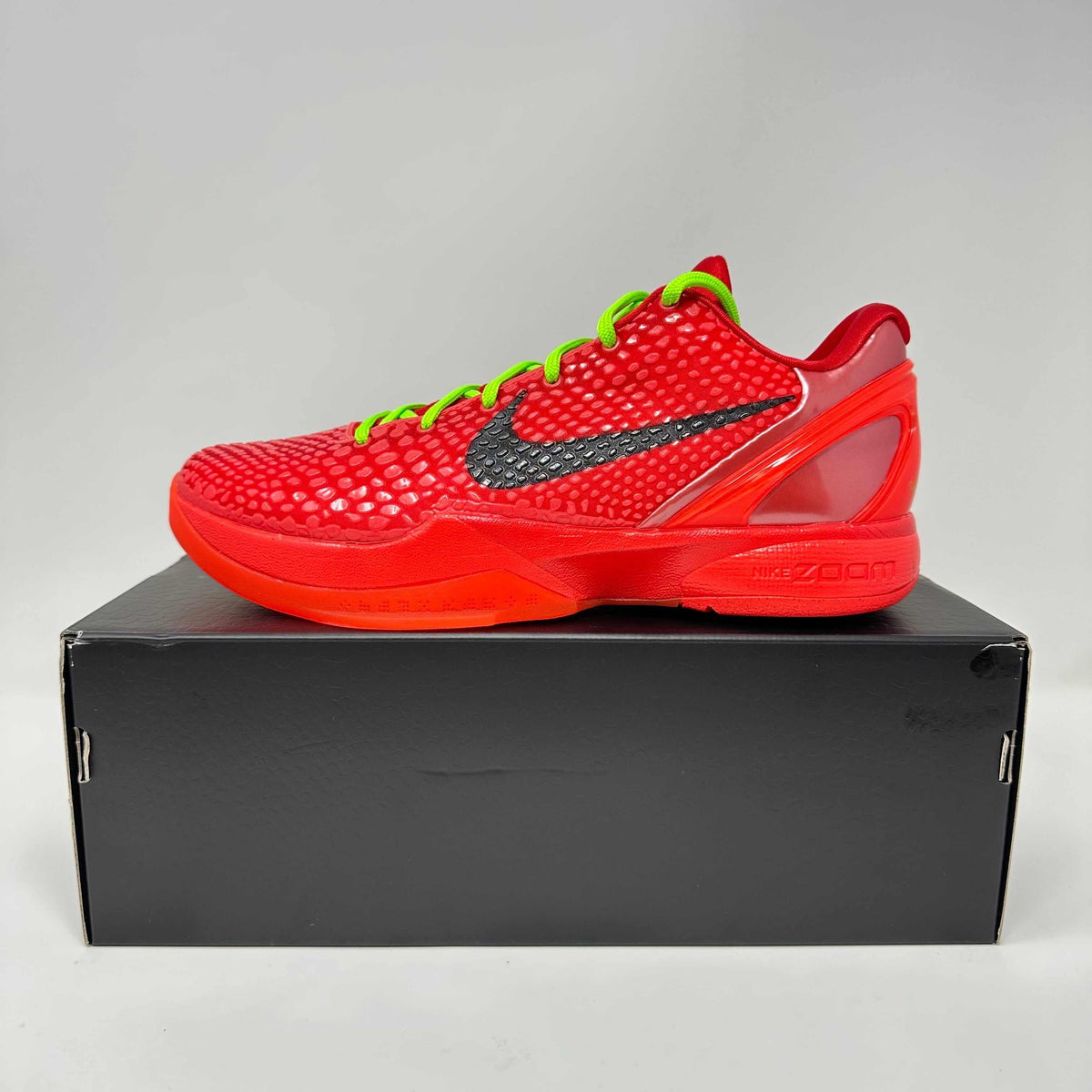 Nike Kobe 6 Protro basketball shoe in bright red with textured upper, black Nike swoosh, and neon green laces on a black box.