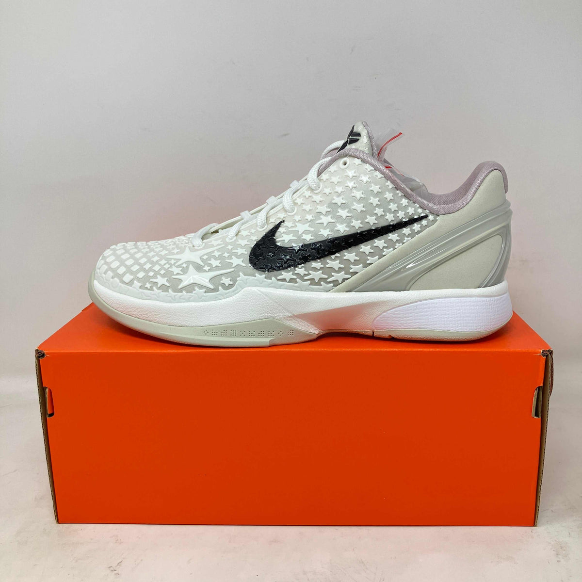 Nike Kobe 6 Sail basketball shoe in white with star pattern, black swoosh, and light grey accents on orange box.