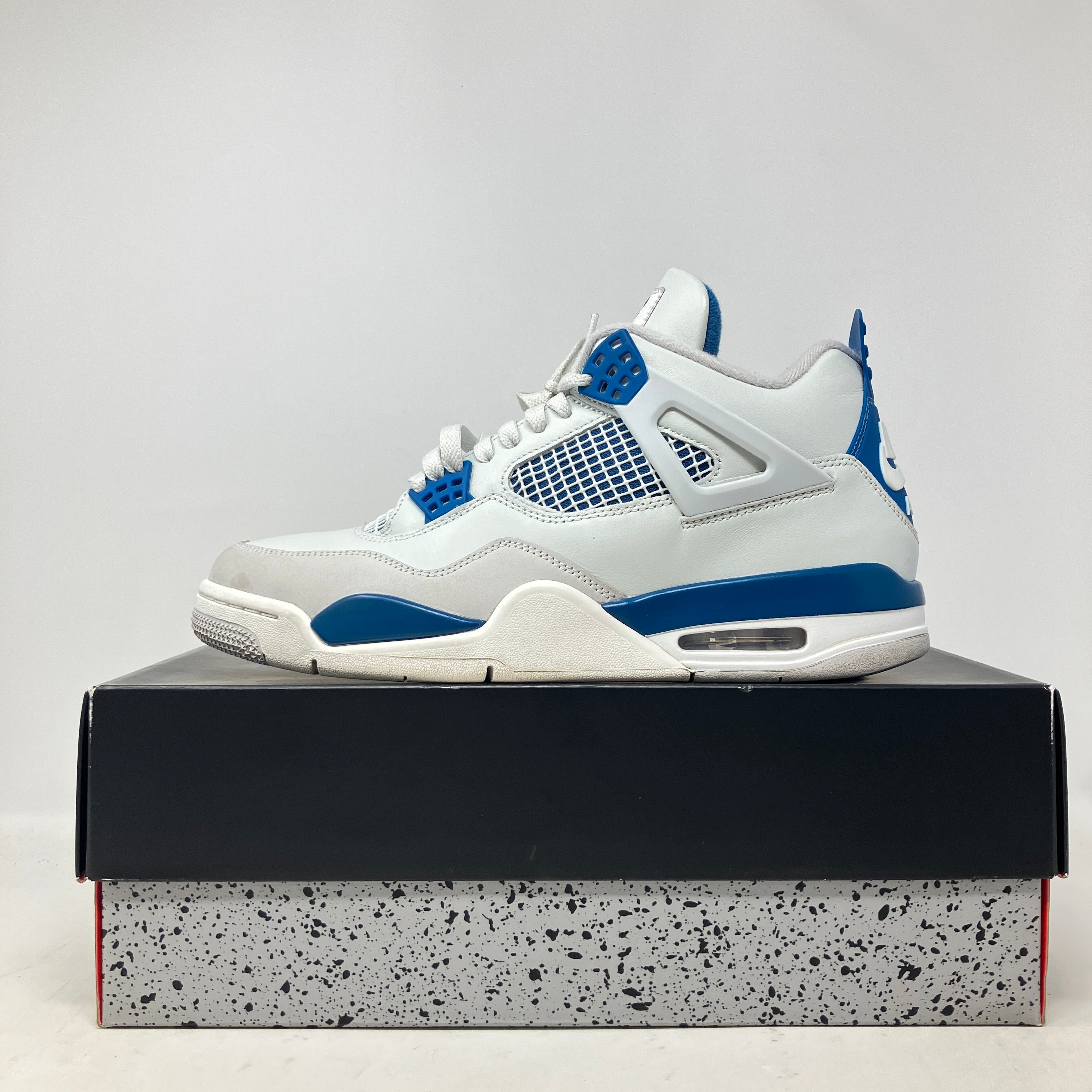 White and military blue Jordan 4 Retro sneaker on black and speckled shoebox, pre-owned condition with all accessories included