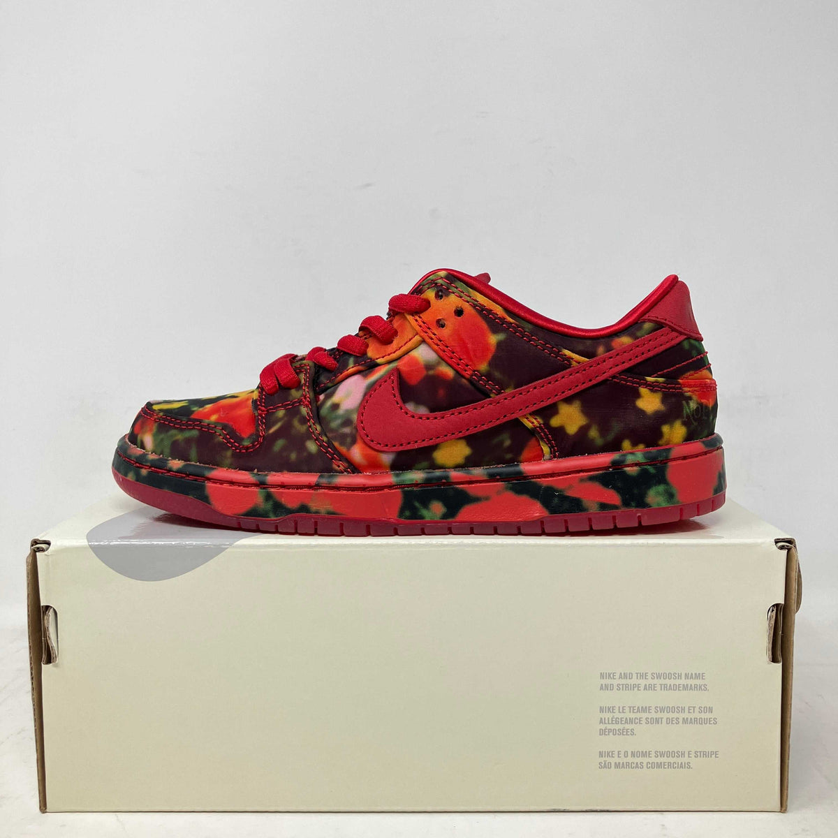 Nike SB Dunk Low children’s sneaker with a red Swoosh and vivid red, orange, and black floral print upper.