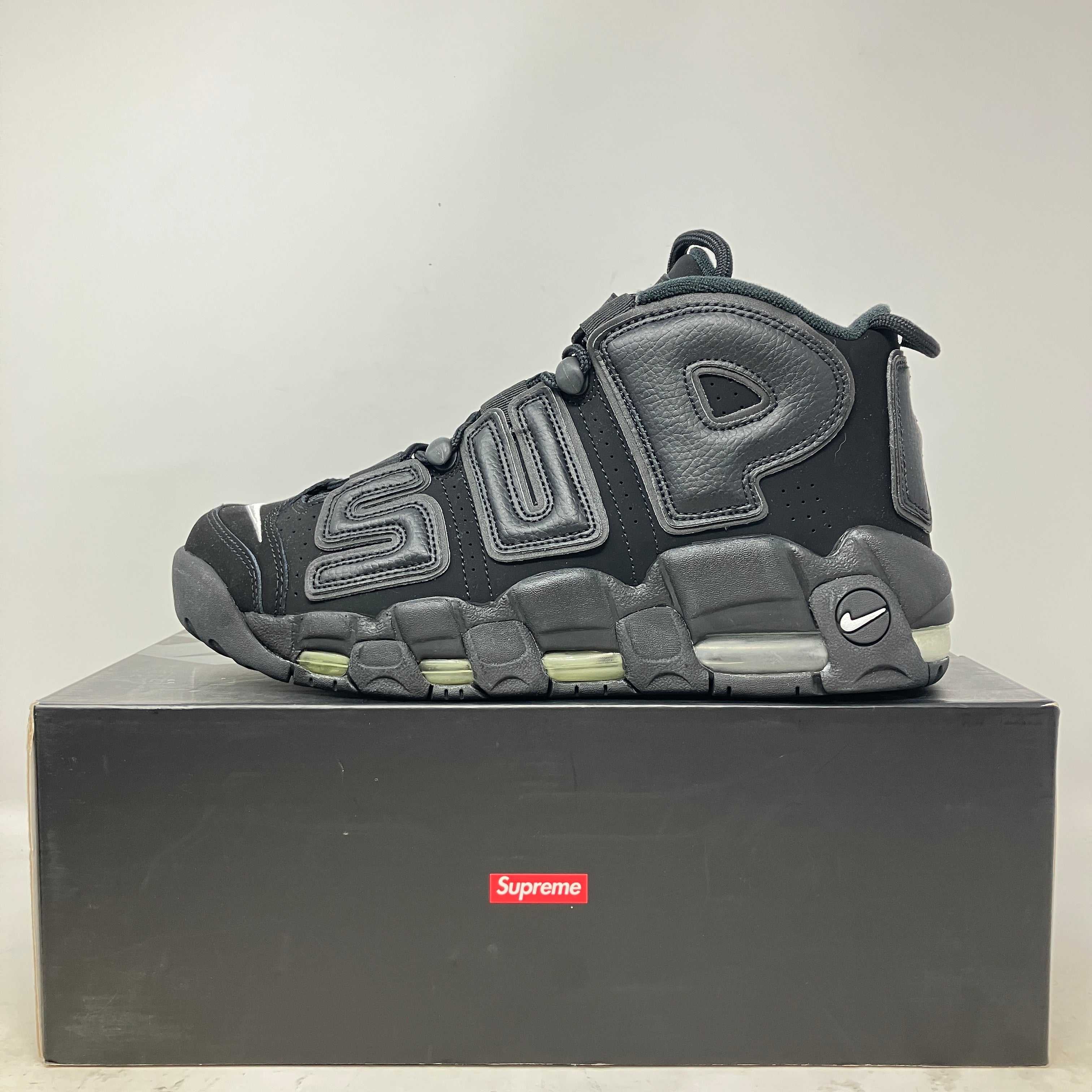 Black Nike Air More Uptempo Supreme sneaker displayed on a Supreme branded box with bold "SUP" lettering on the side.