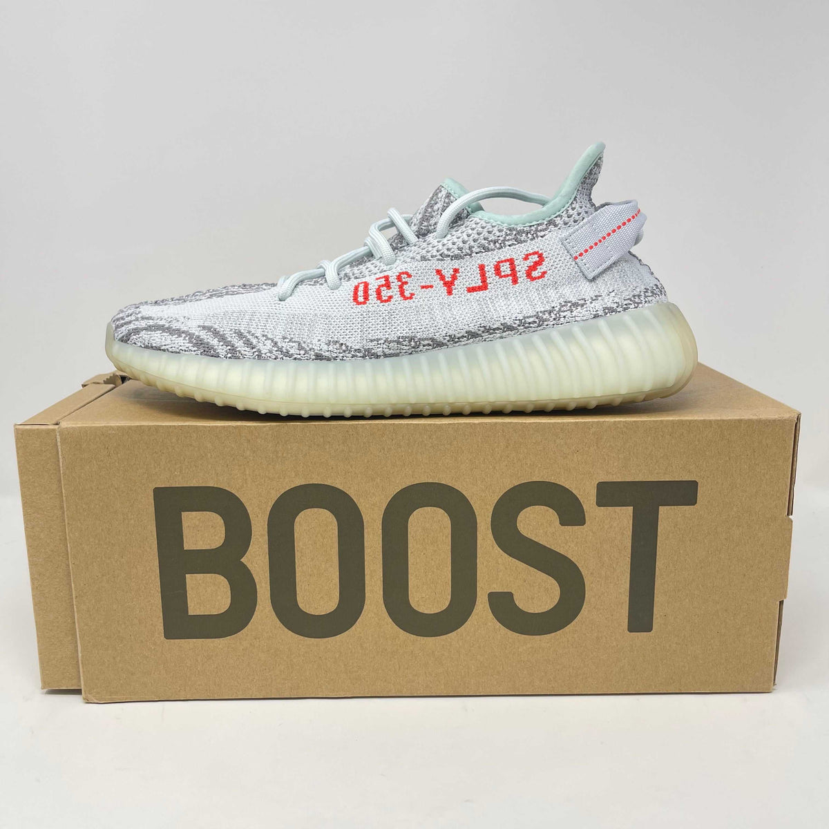 adidas Yeezy Boost 350 V2 sneaker in blue tint with grey and red accents, semi-translucent cream sole, and knit fabric upper