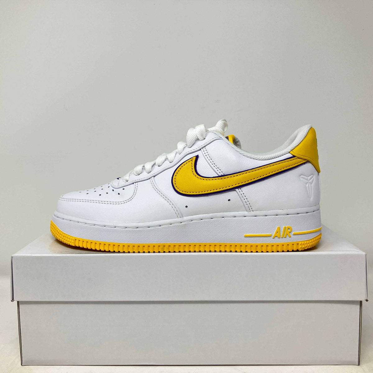 Nike Air Force 1 Low white leather sneaker with yellow accents, yellow swoosh, and perforated toe box design