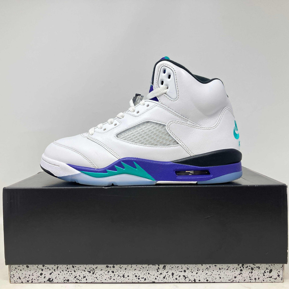 Jordan 5 Retro Grape sneaker in white leather with gray mesh panels, purple midsole, teal accents and visible heel logo