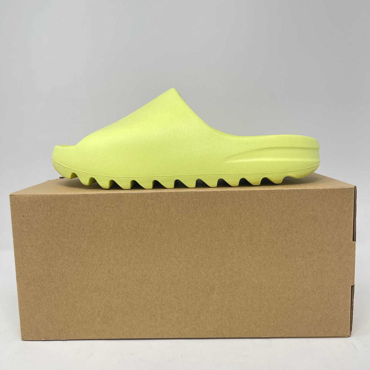adidas Yeezy Slide in bright glow green foam with a smooth, sculpted open-toe design and ridged sole.