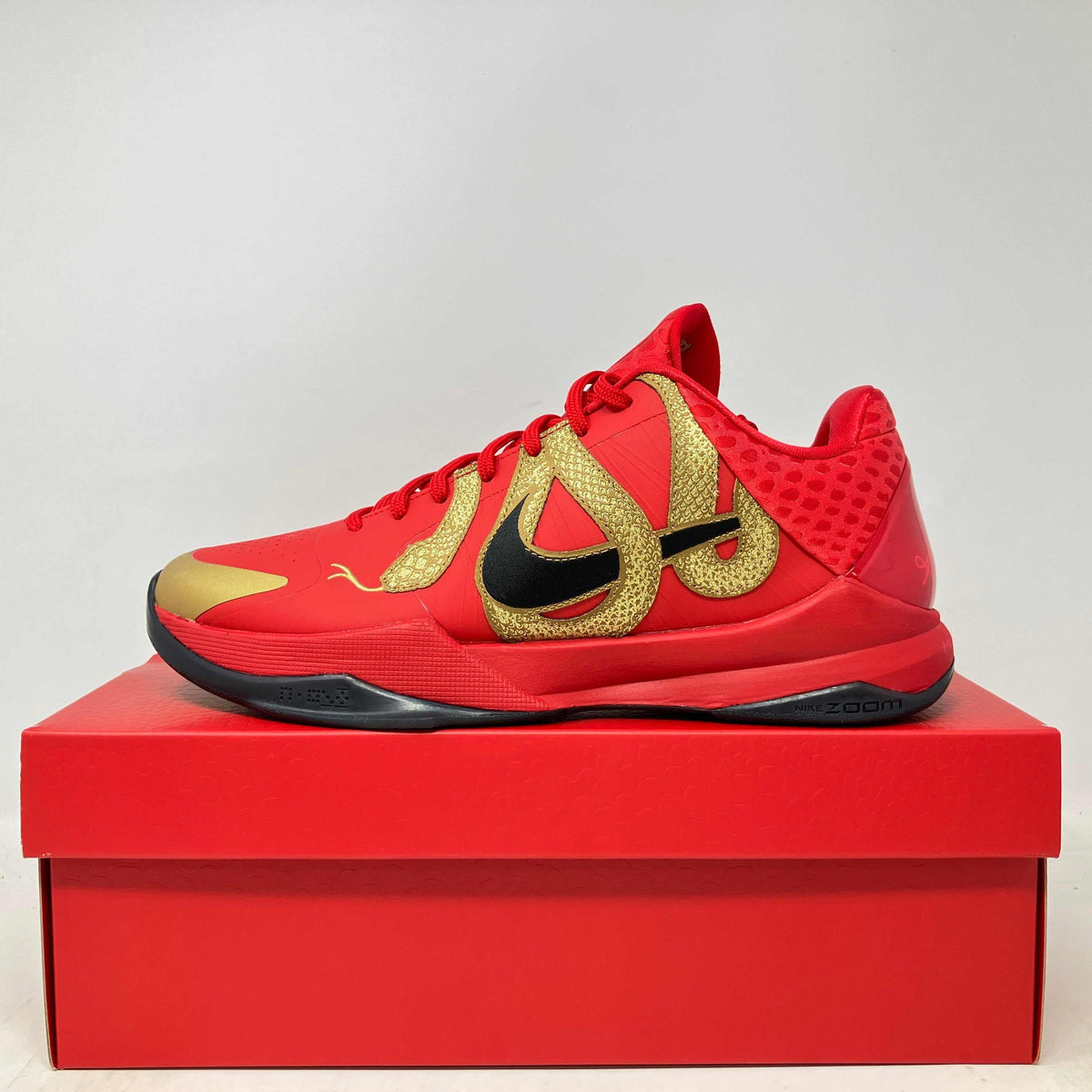 Nike Kobe 5 Protro basketball shoe in university red with gold and black accents, featuring textured patterns and a sleek design.