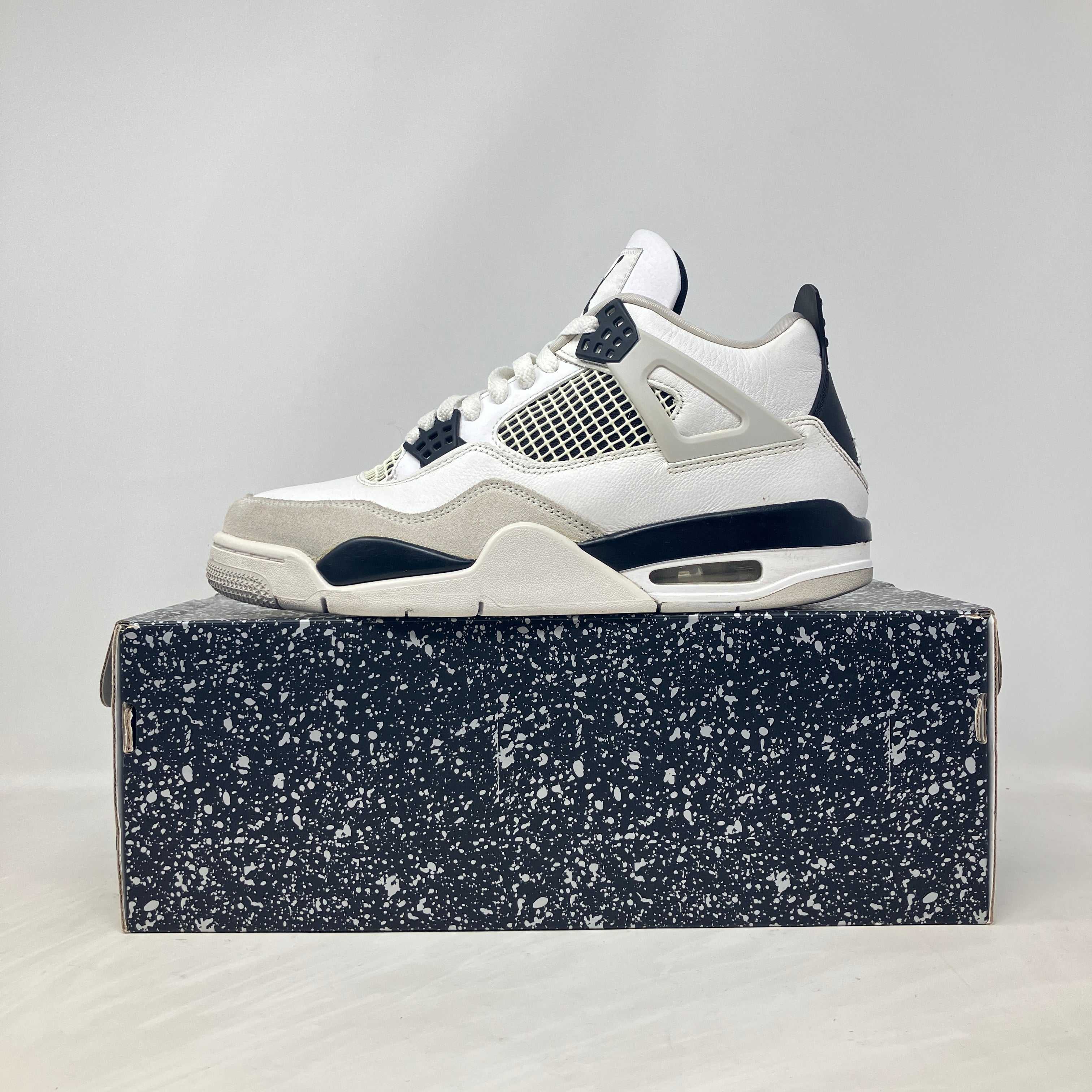 Jordan 4 Retro Military Black sneaker on speckled black box, pre-owned with accessories included