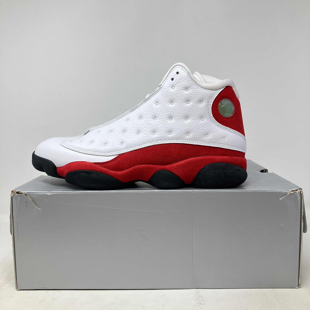 Jordan 13 Retro OG Chicago basketball shoe in white leather with red suede and black sole detailing with holographic emblem.