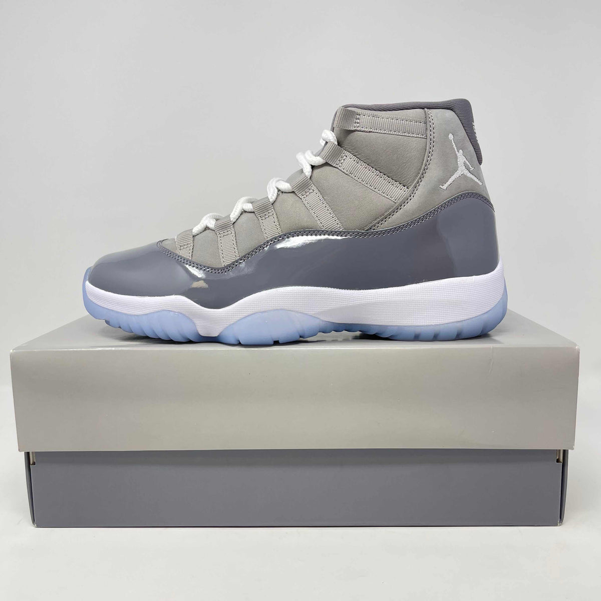 Jordan 11 Retro Cool Grey sneaker in shades of grey with patent leather and mesh upper, white sole, and icy blue outsole.