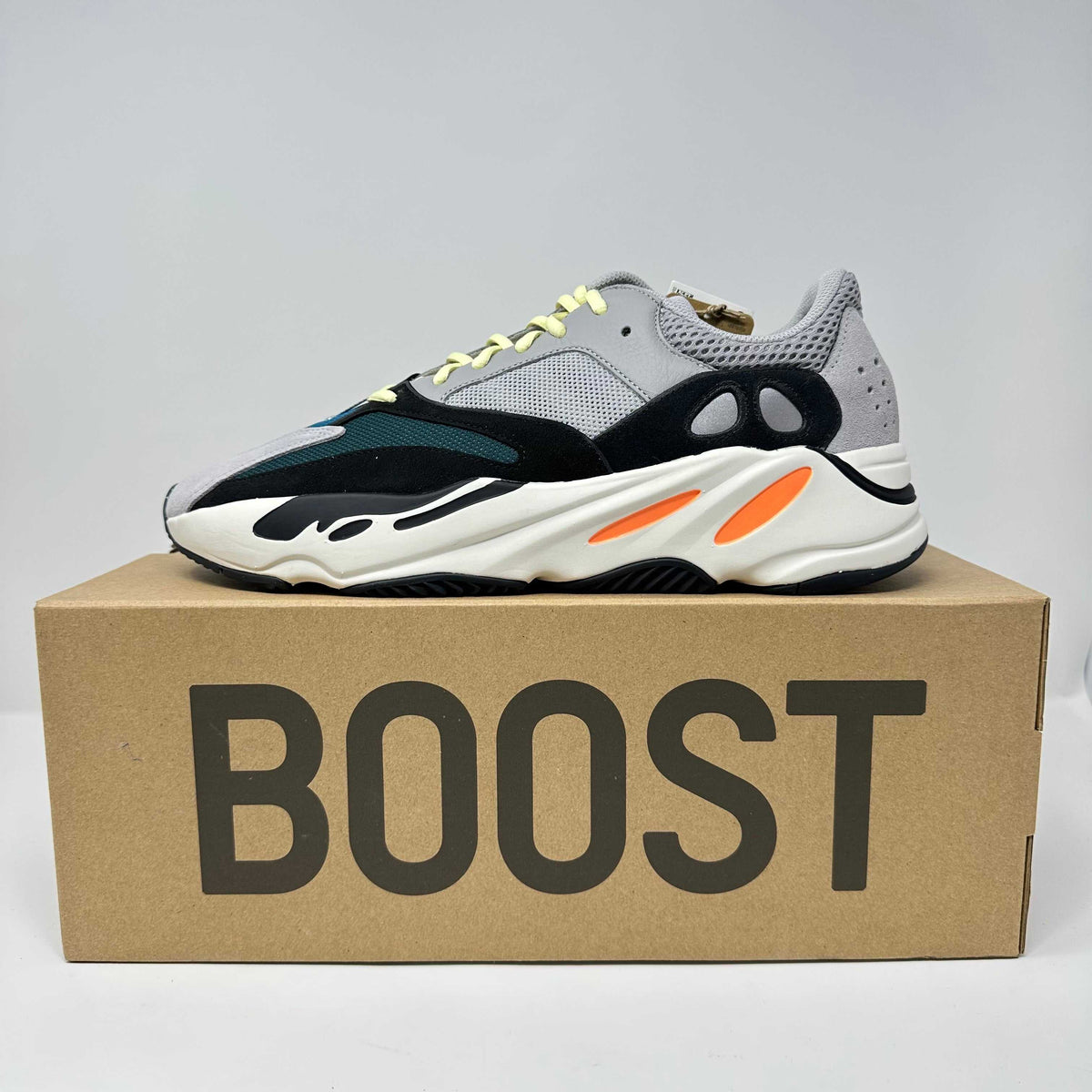adidas Yeezy Boost sneaker in black, grey, white, and orange with mesh and suede materials, featuring chunky sole and neon yellow laces