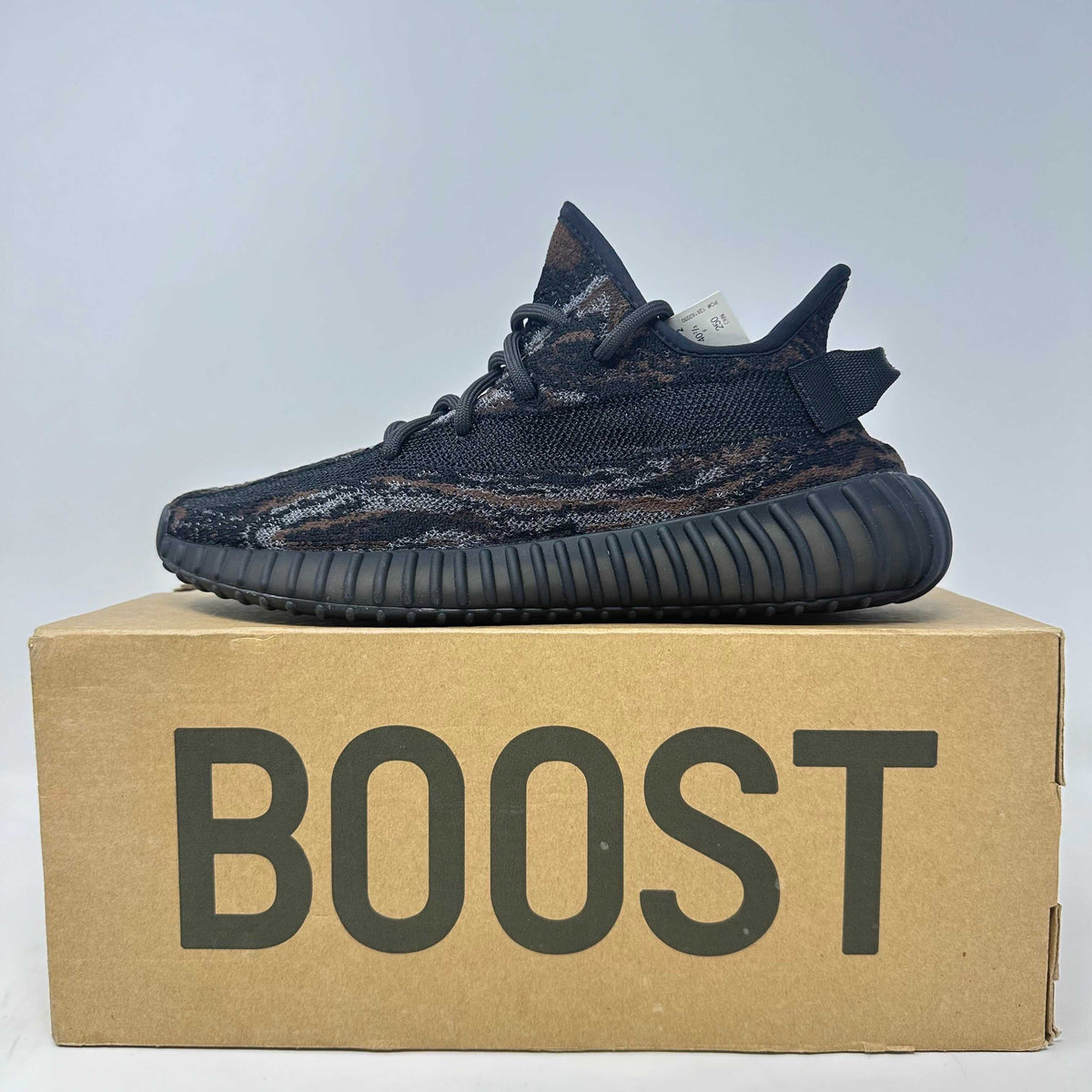 adidas Yeezy Boost black and dark brown knit sneakers with textured pattern and ribbed sole on Boost box