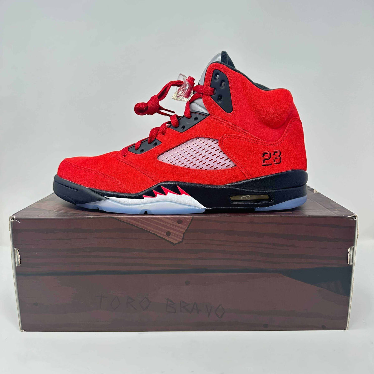 Jordan 5 Retro red suede basketball shoe with black accents, mesh side panel, and distinctive "23" embroidery on heel.