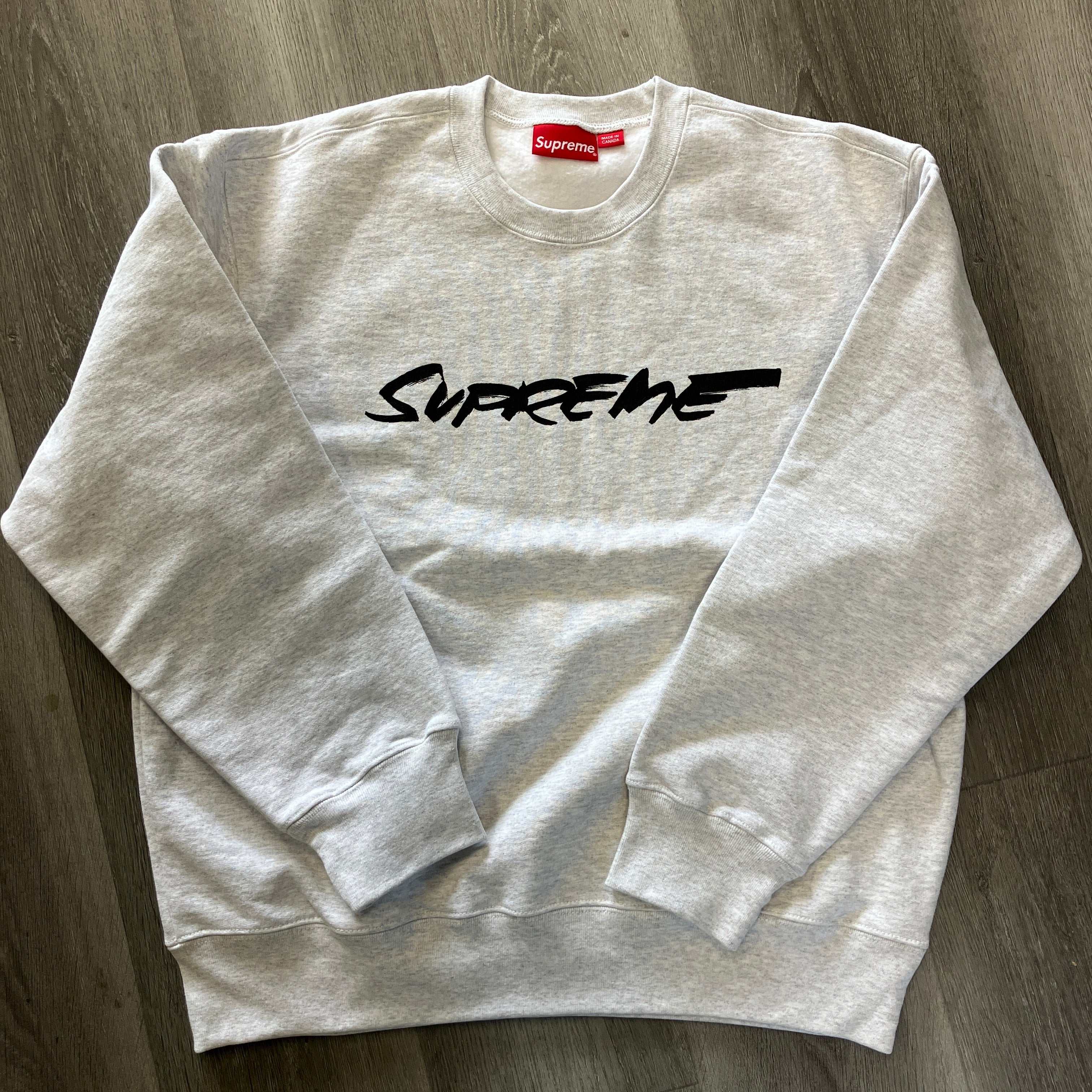 Supreme Futura Logo ash grey crewneck sweatshirt flat lay on wooden floor