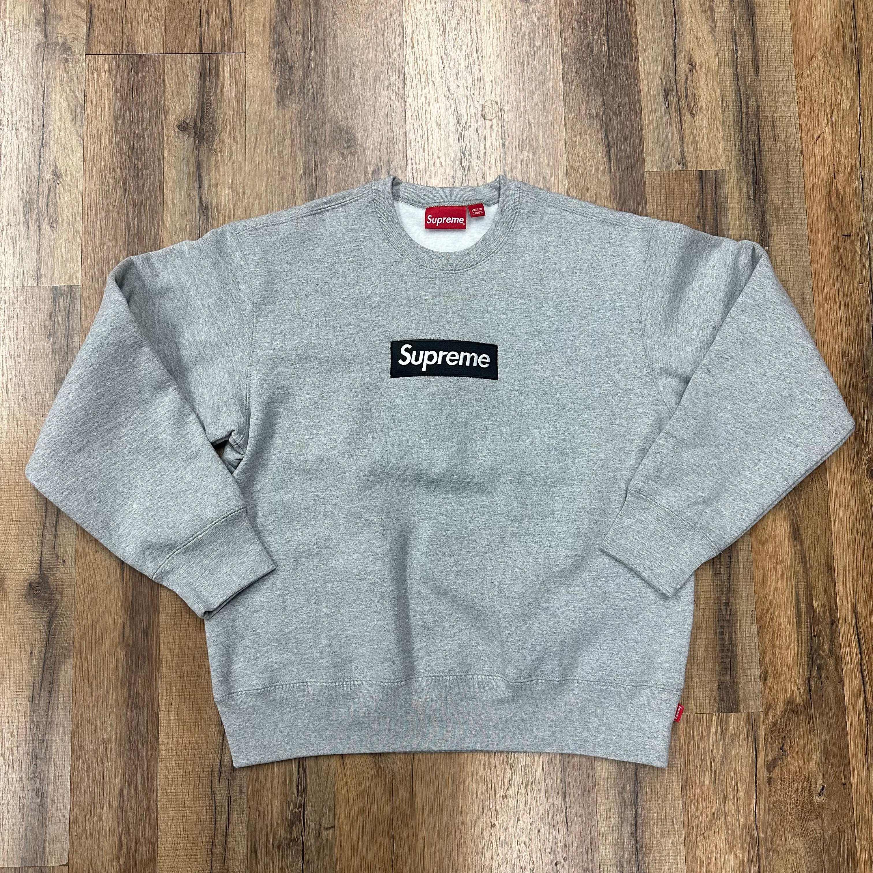 Heather grey Supreme Box logo crewneck sweatshirt laid flat on wooden floor