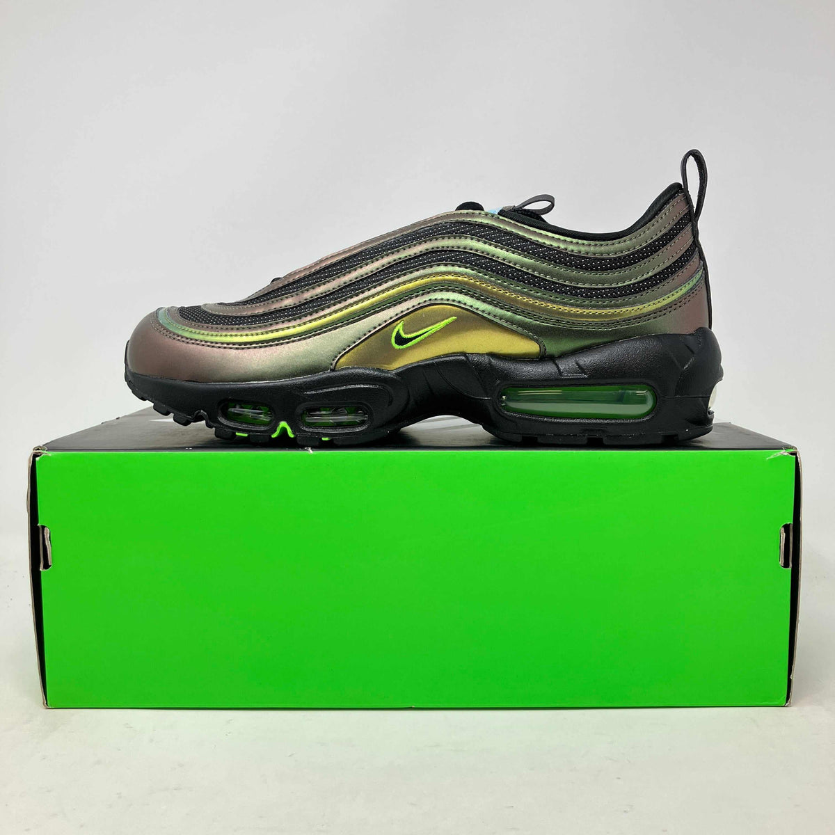 Nike Air Max 95 sneaker in iridescent green and black with neon green accents and visible air cushioning on a bright green box.