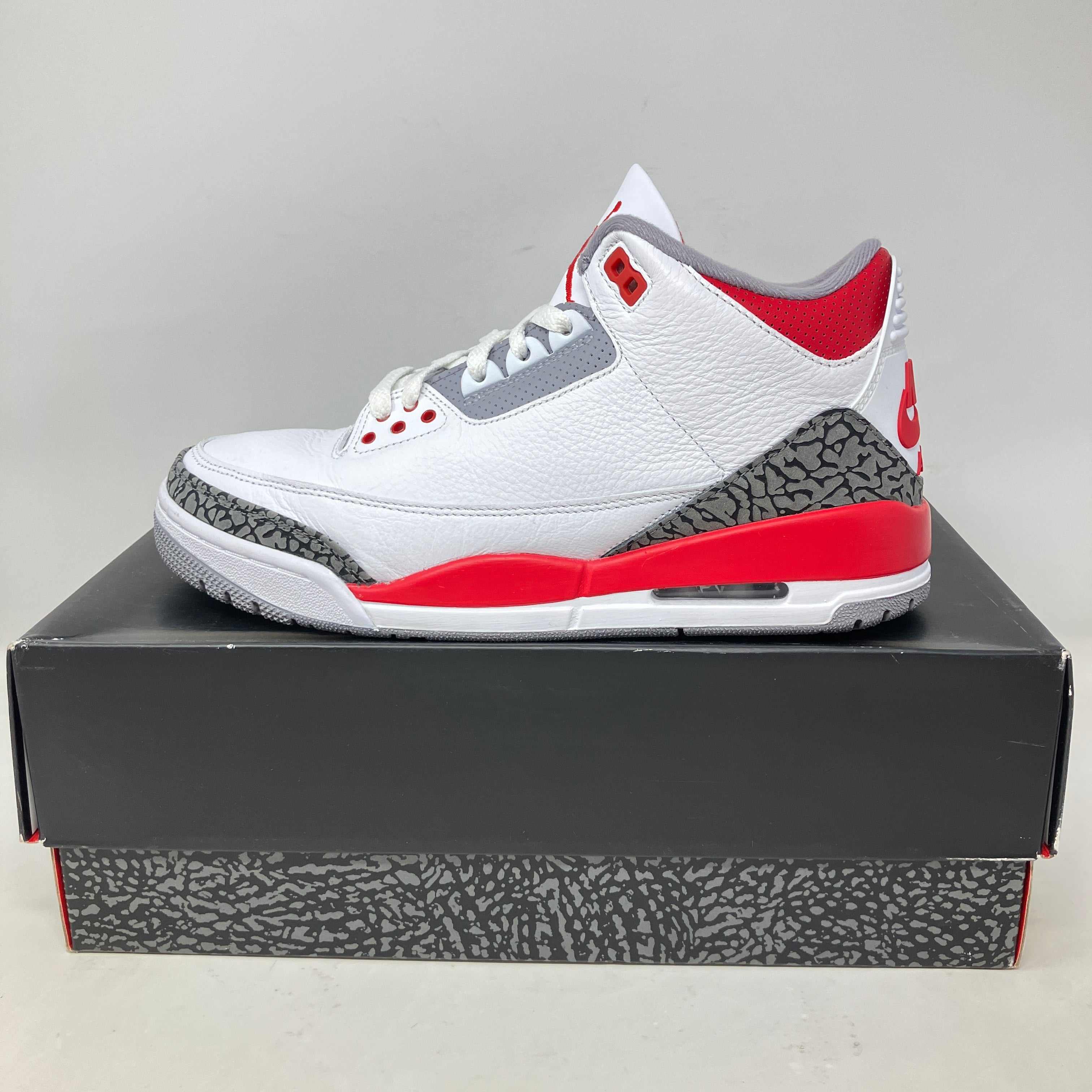 Jordan 3 Retro Fire Red (2022) sneaker in white, red, and gray on black shoe box with elephant print details