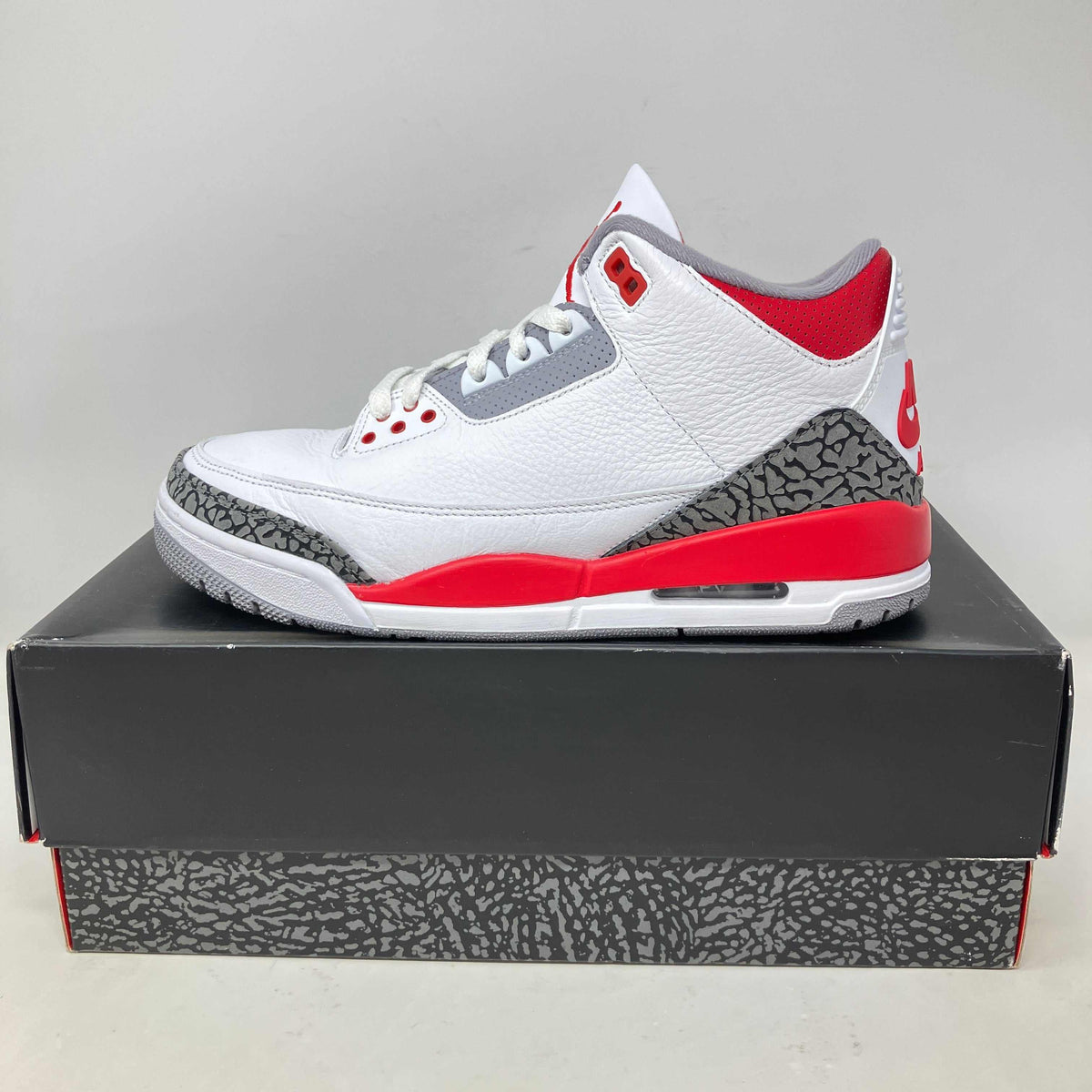 Jordan 3 Retro Fire Red sneaker in white pebbled leather with red accents, grey elephant-print overlays, and visible Air sole.