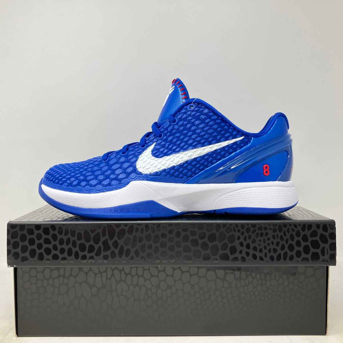 Nike Kobe 6 Dodgers basketball shoe in vivid blue textured mesh with a white Swoosh, white midsole, and red accents.