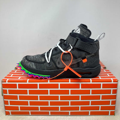 Nike Air Force 1 Mid black high-top sneaker with gray patterns, multicolor spikes on the sole, and an orange zip tie accessory.