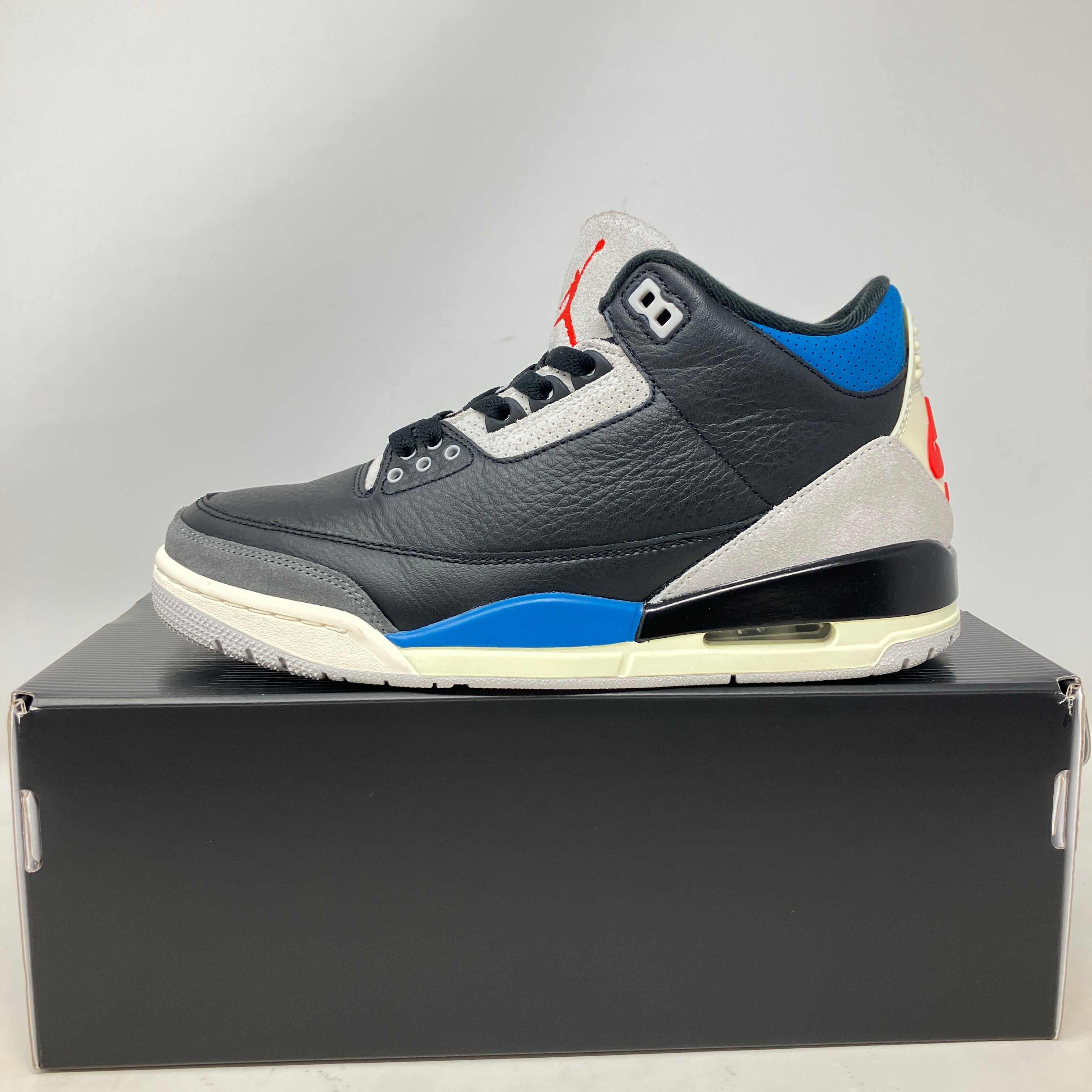 Black and blue Jordan 3 Retro OG Rare Air sneaker displayed on a black box, pre-owned condition with all accessories included
