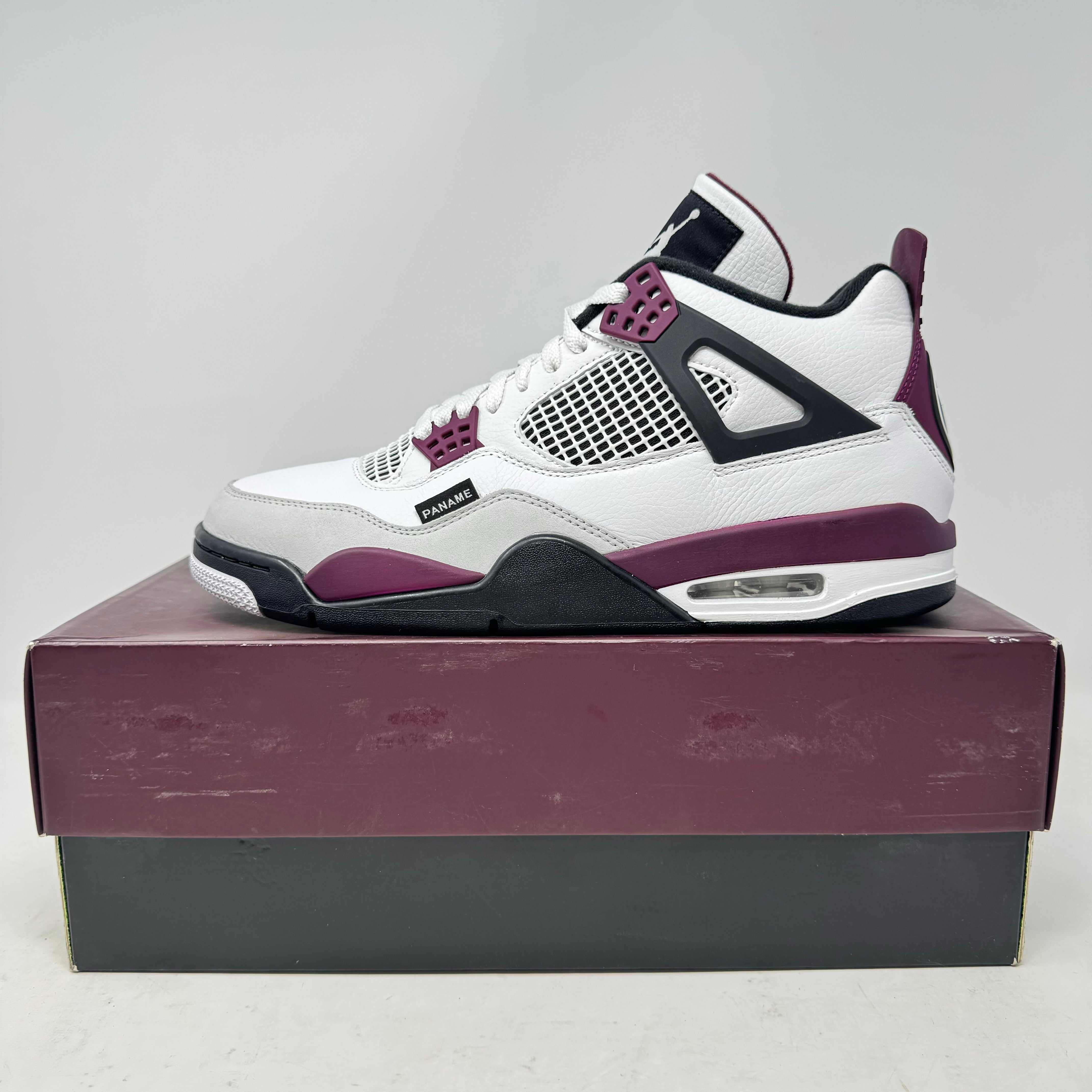 White and purple Jordan 4 Retro PSG Paris Saint-Germain sneaker on box, pre-owned condition